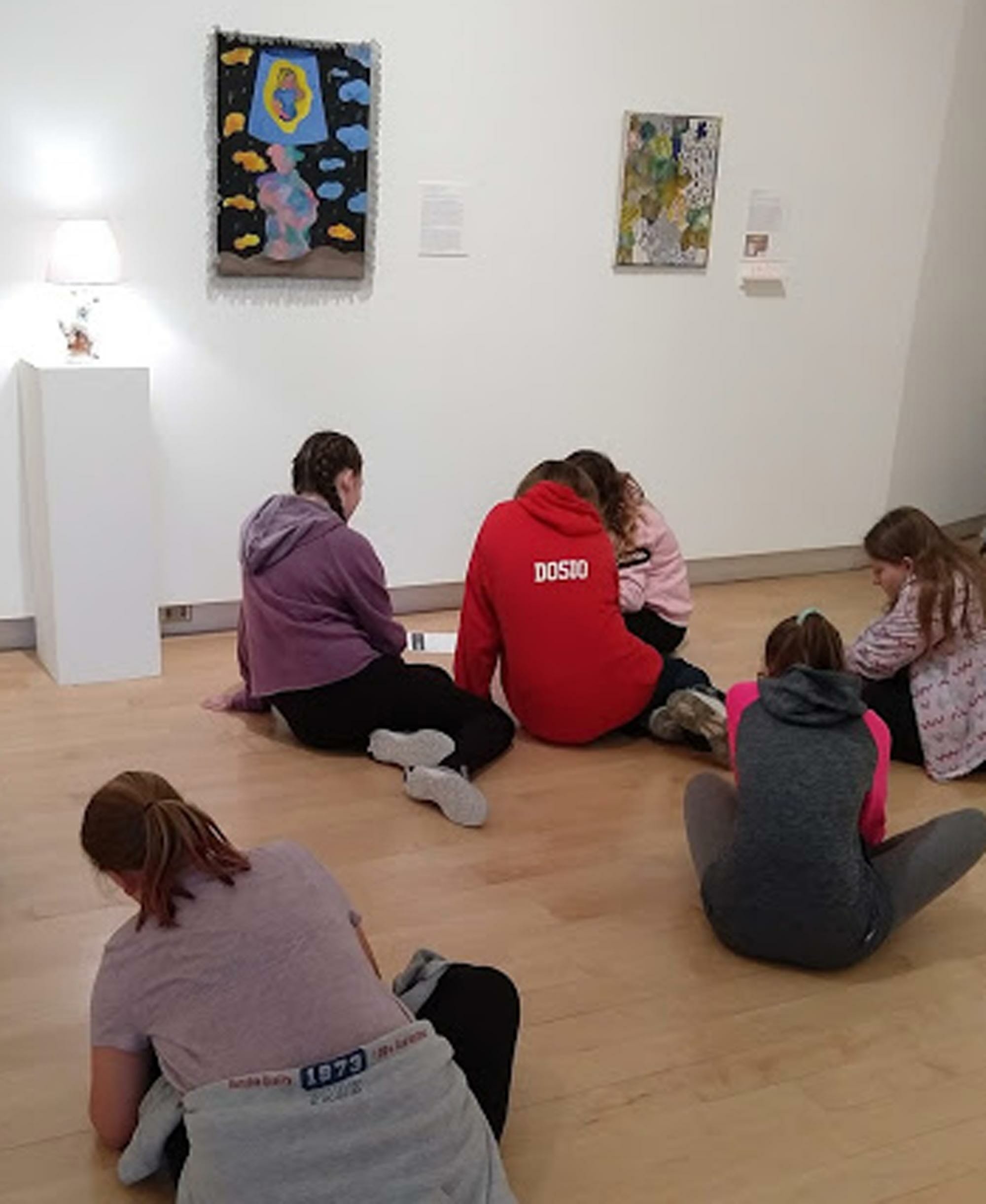 Six Girl Scouts seated on the floor of the Museum, doing a creative activity