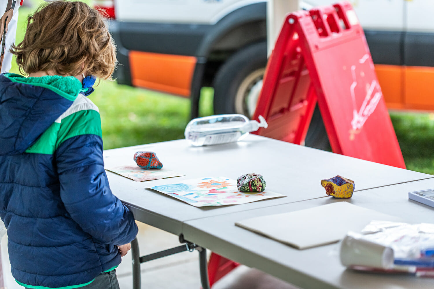 kid looking at painted rocks on a table