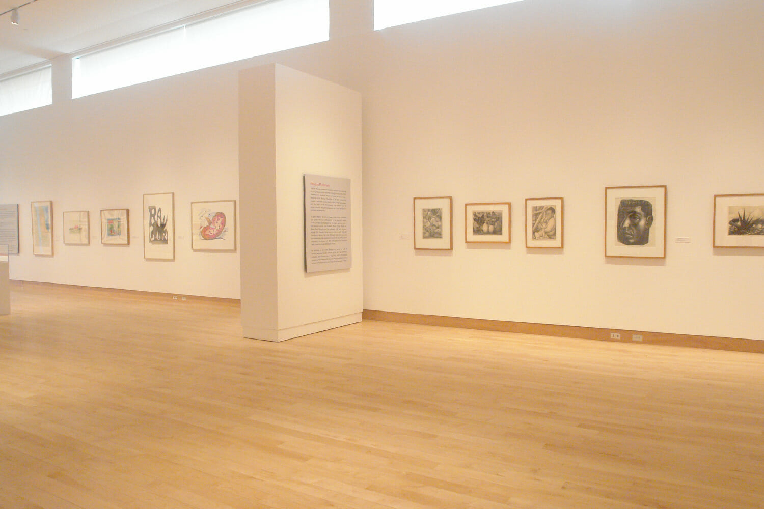 installation view of "In Depth," featuring ten framed artworks hanging across a wall with exhibition text