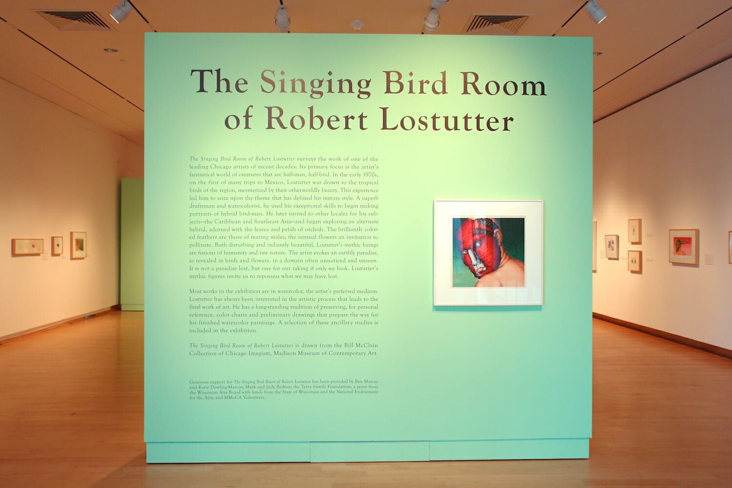 installation view of "The Singing Bird Rooms of Robert Lostutter" with title wall text and a framed work of art