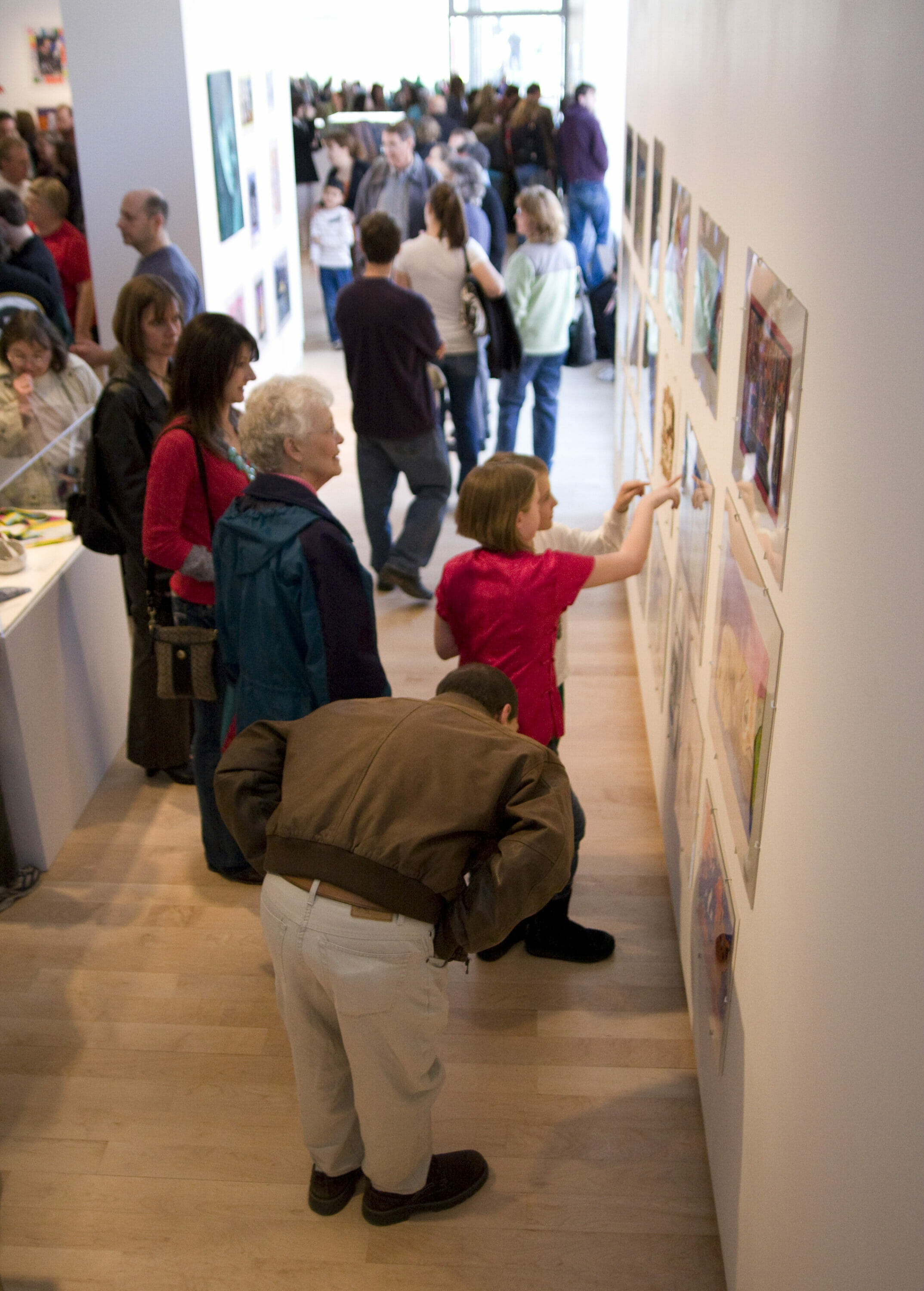 gallery visitors looking at artwork made by children displayed on walls