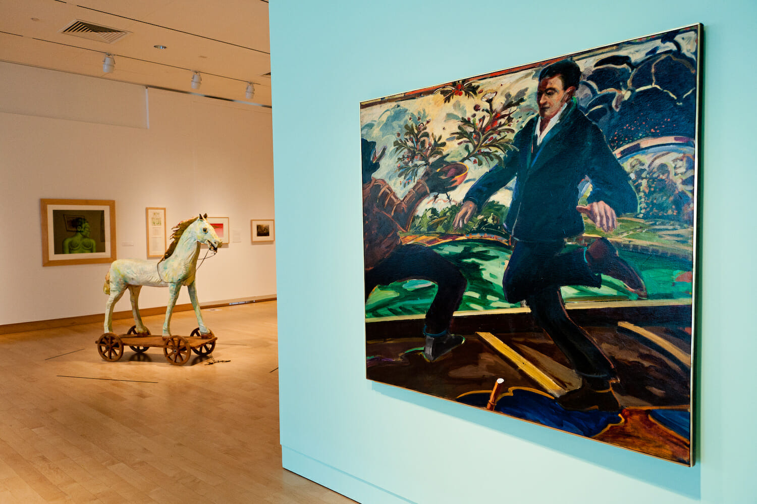 installation view of the exhibition Chicago School featuring a house sculpture, a large painting near the foreground, and artworks hanging vertically across walls