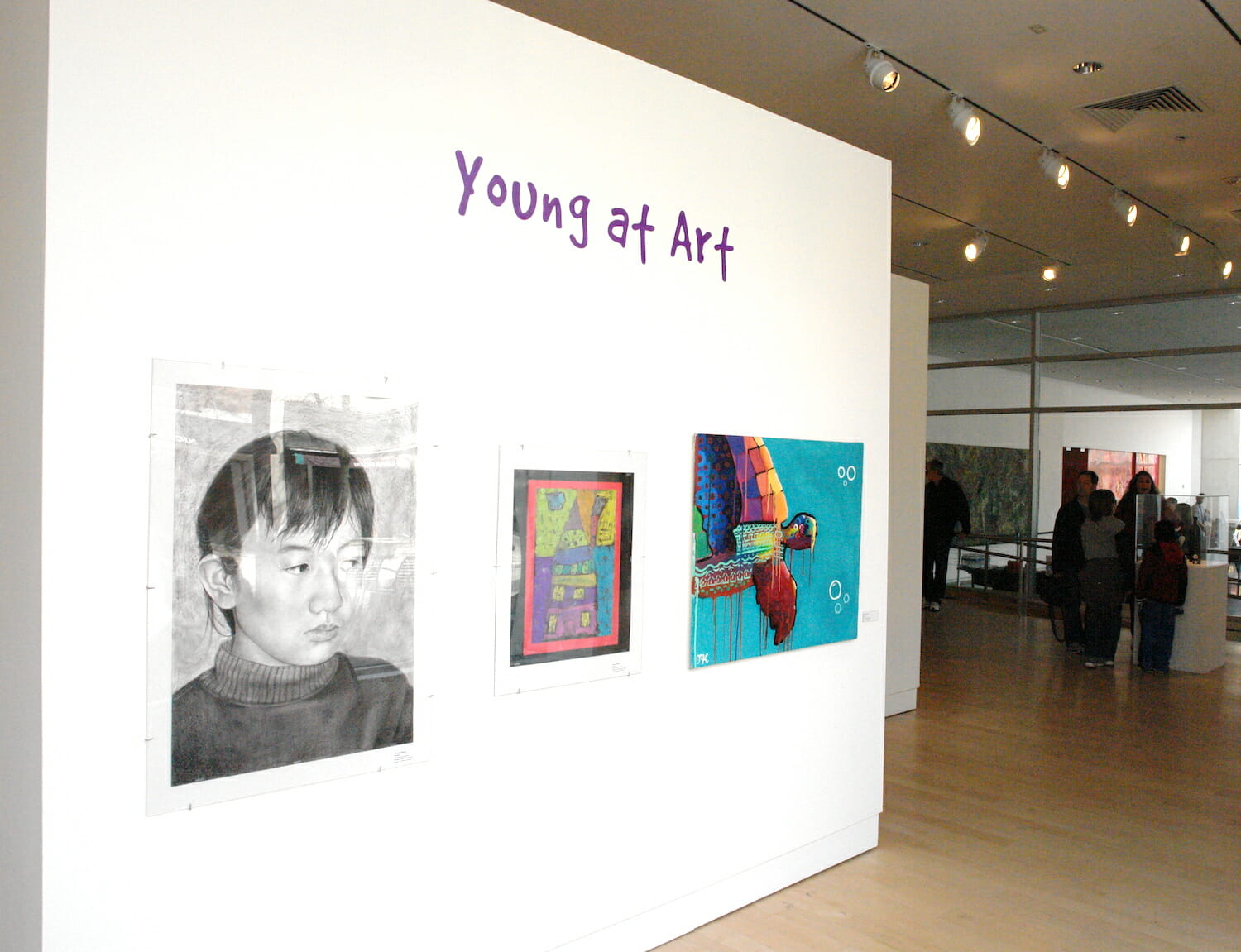 installation view of the 2013 Young at Art exhibition featuring three artworks by children on display across a wall
