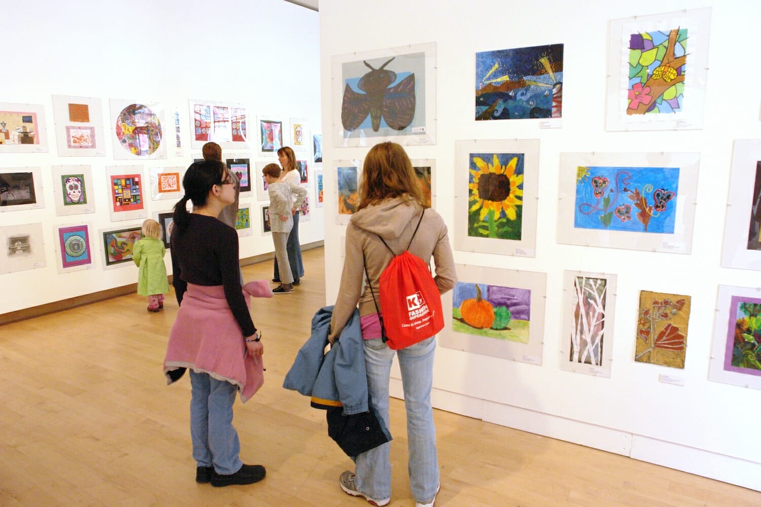 children and families looking at artworks by children on display across a wall