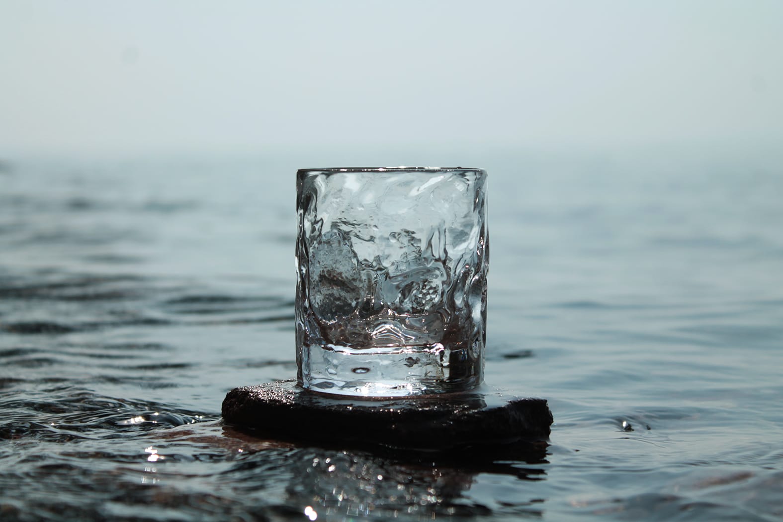 a photo of a glass on a rock in water