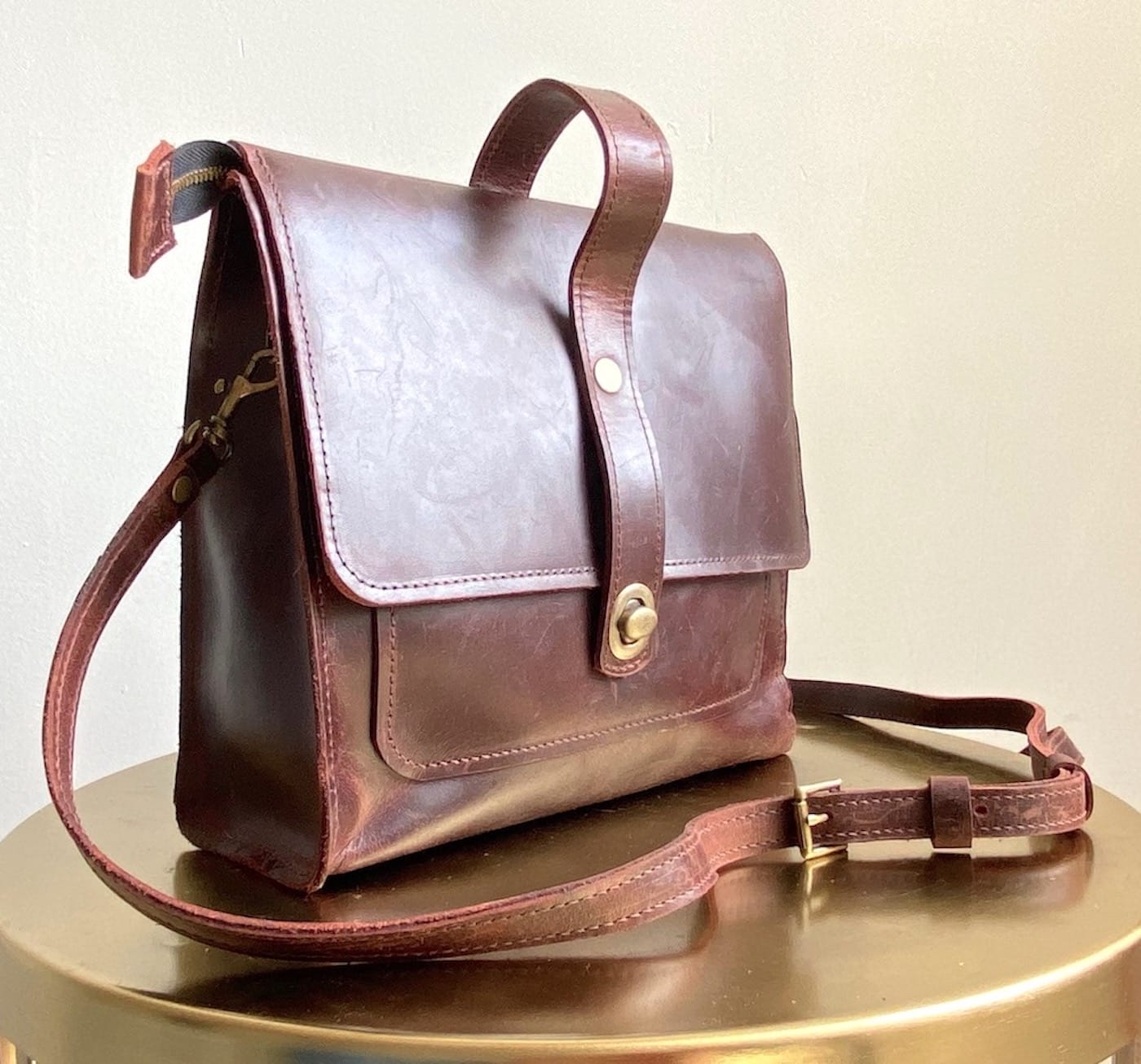 a leather tote bag on a gold surface.