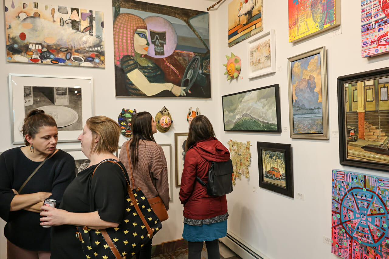 People standing in an art gallery while looking at artwork.