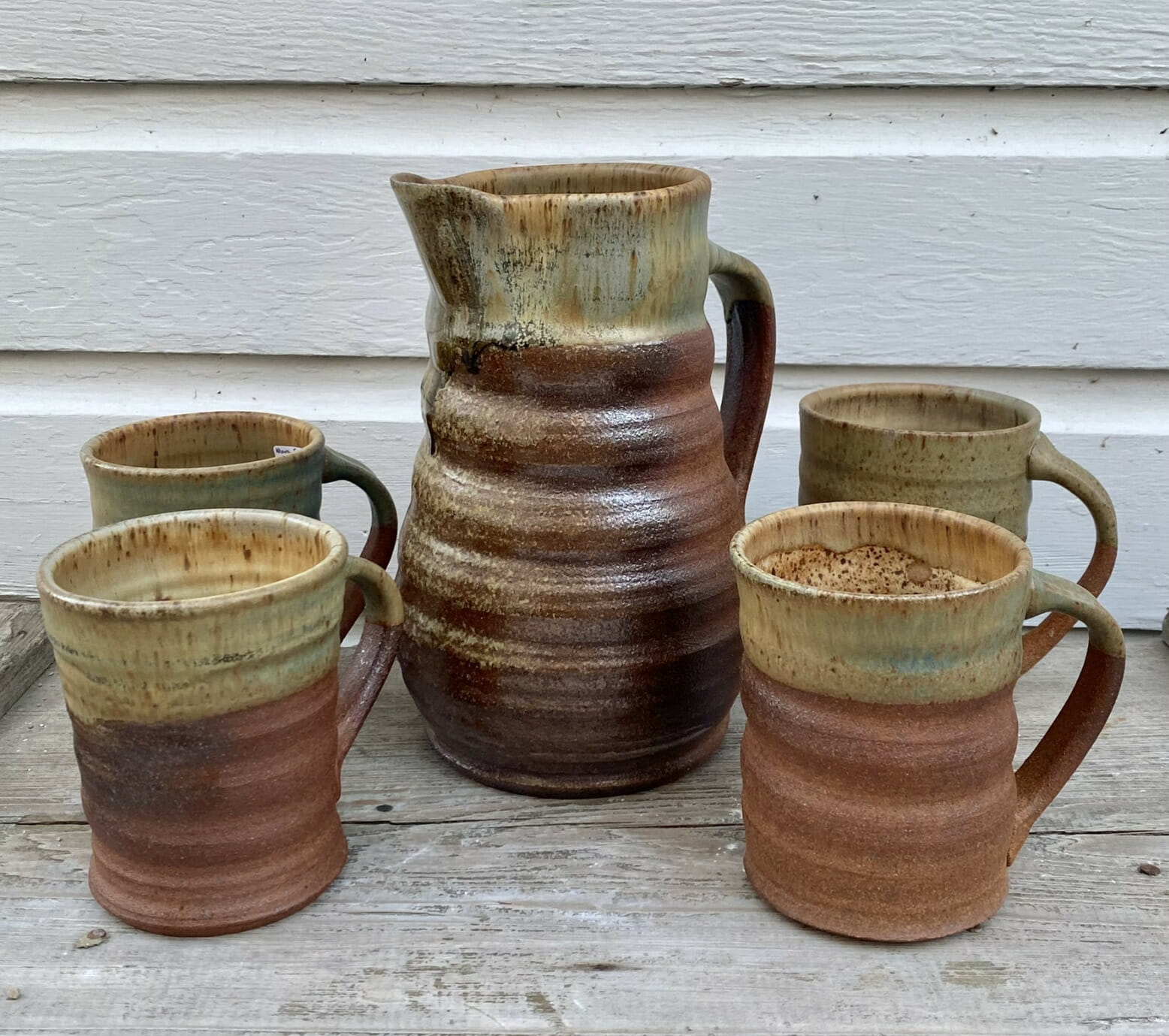 A pitcher and four ceramic mugs.