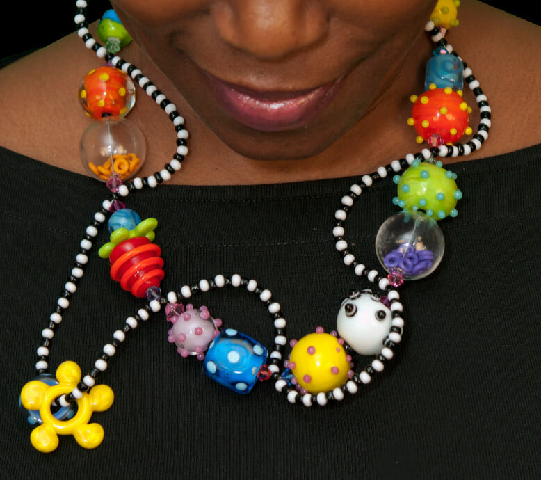 A person wearing a necklace with jumbo glass beads.