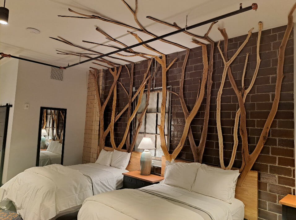 Wooden art attached to headboards which trail up the wall and across part of the ceiling.