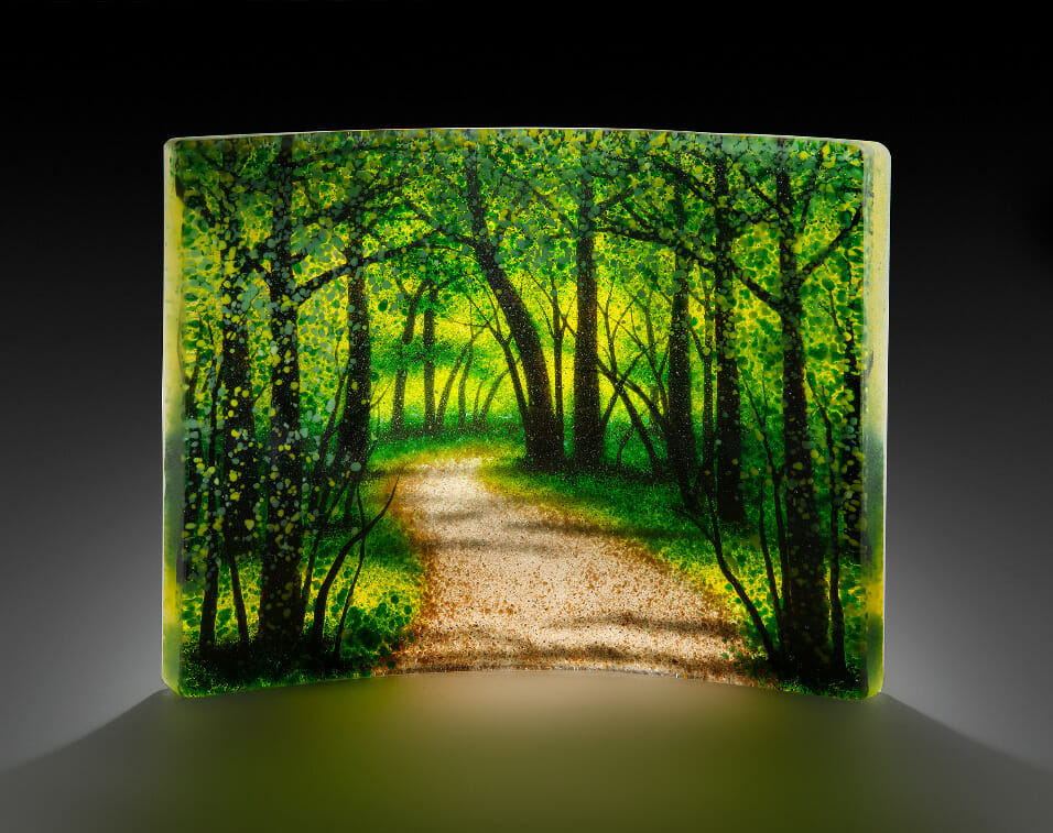 Glass art with imagery of a path going through a forest
