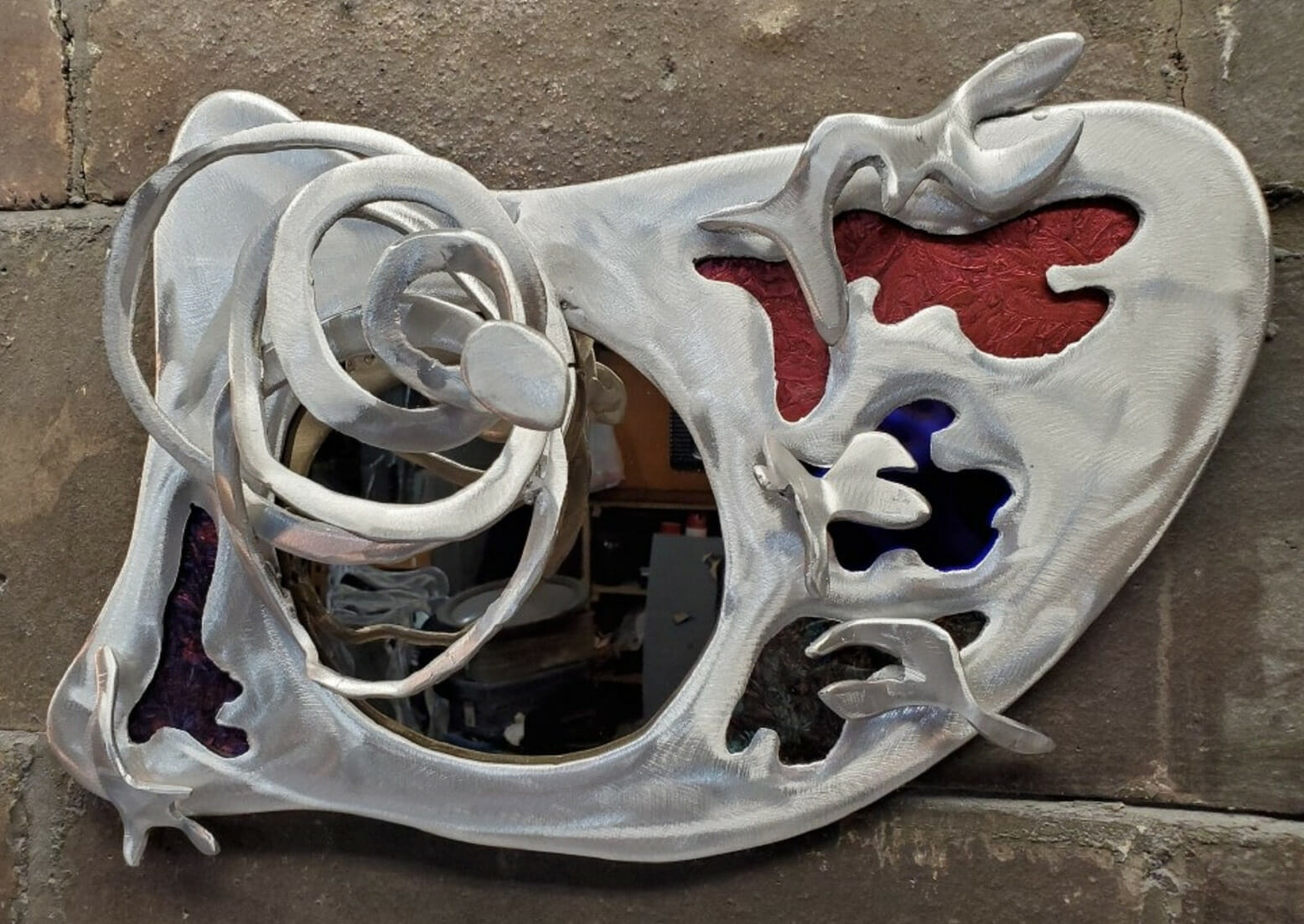 Handcut aluminum with stained glass and mirror inserts, creating a unique design.