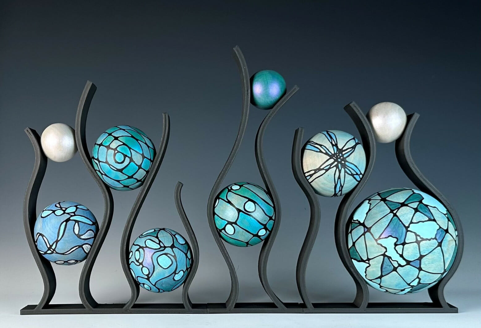 Wooden sculpture with hand painted wood spheres featuring various patterns and designs.
