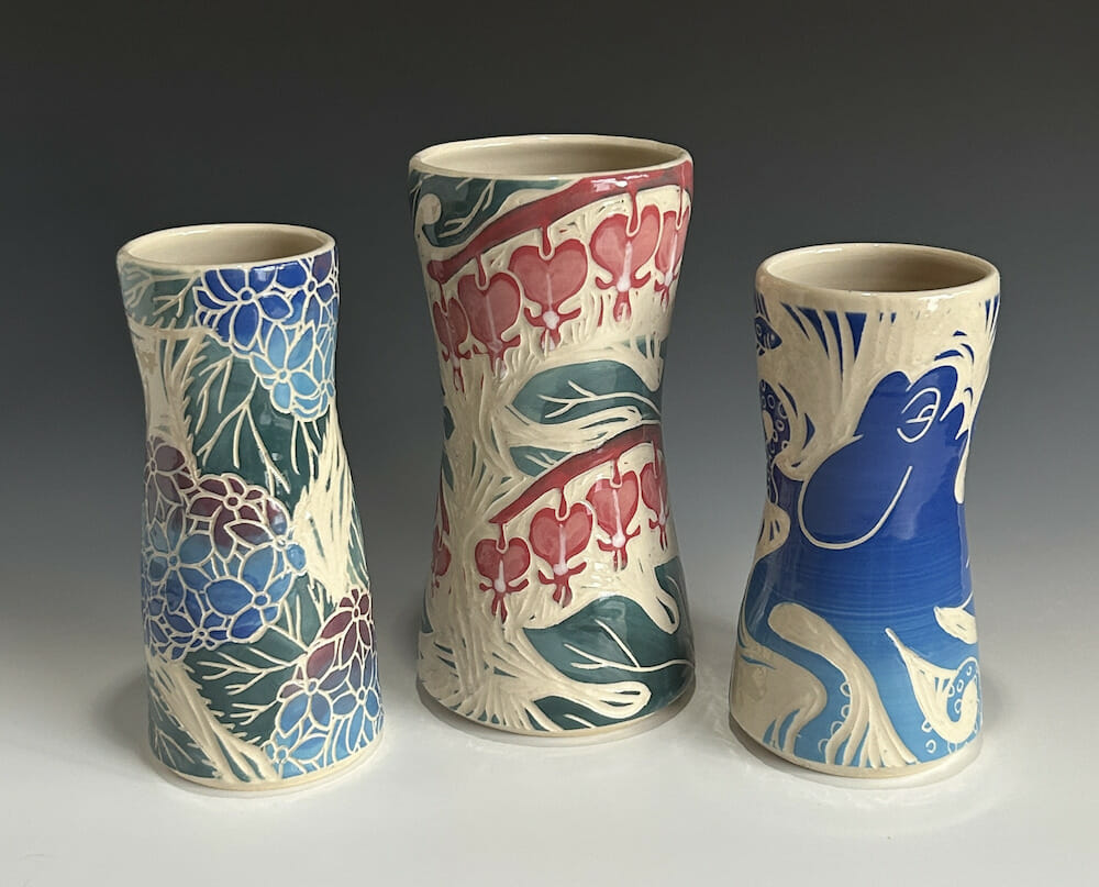 Three ceramic vases with carved floral designs or an octopus design.
