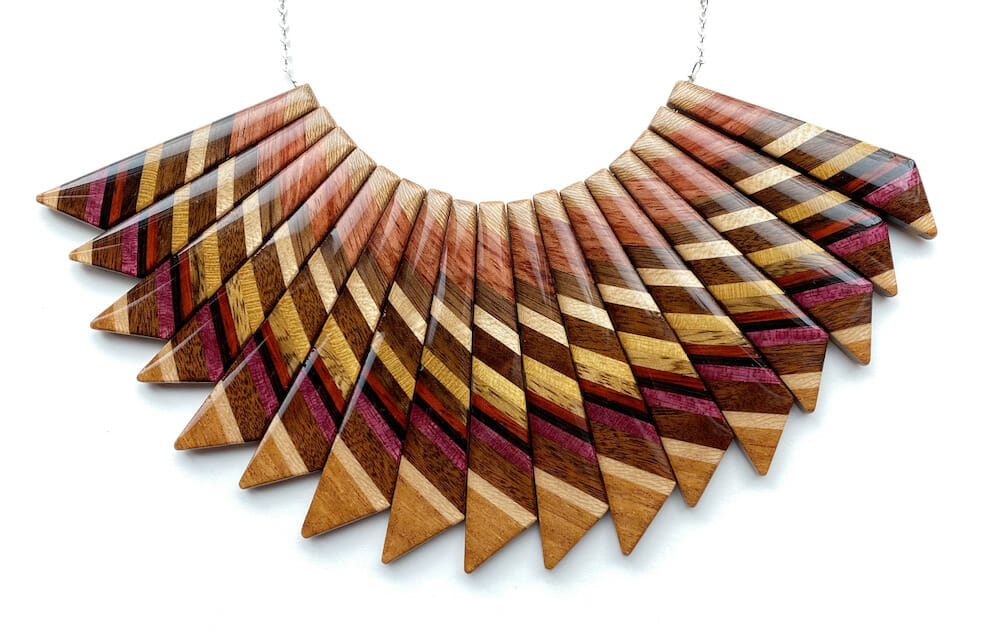 Staple necklace with seventeen striped wooden pendants with a clear resin coating.