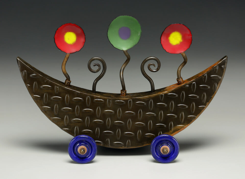 Metal sculpture resembling a crescent shape on wheels