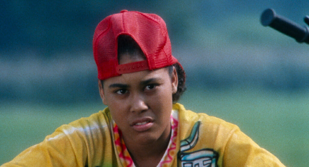 Film still from Alma's Rainbow showing a person wearing a backwards cap, making a facial expression.