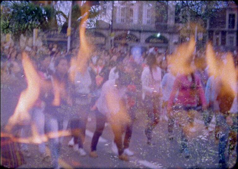A blurry image of a crown of people on the street with fire imagery superimposed.