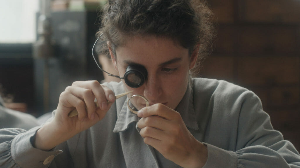 A person looking through a loope at a piece of a mechanical watch.