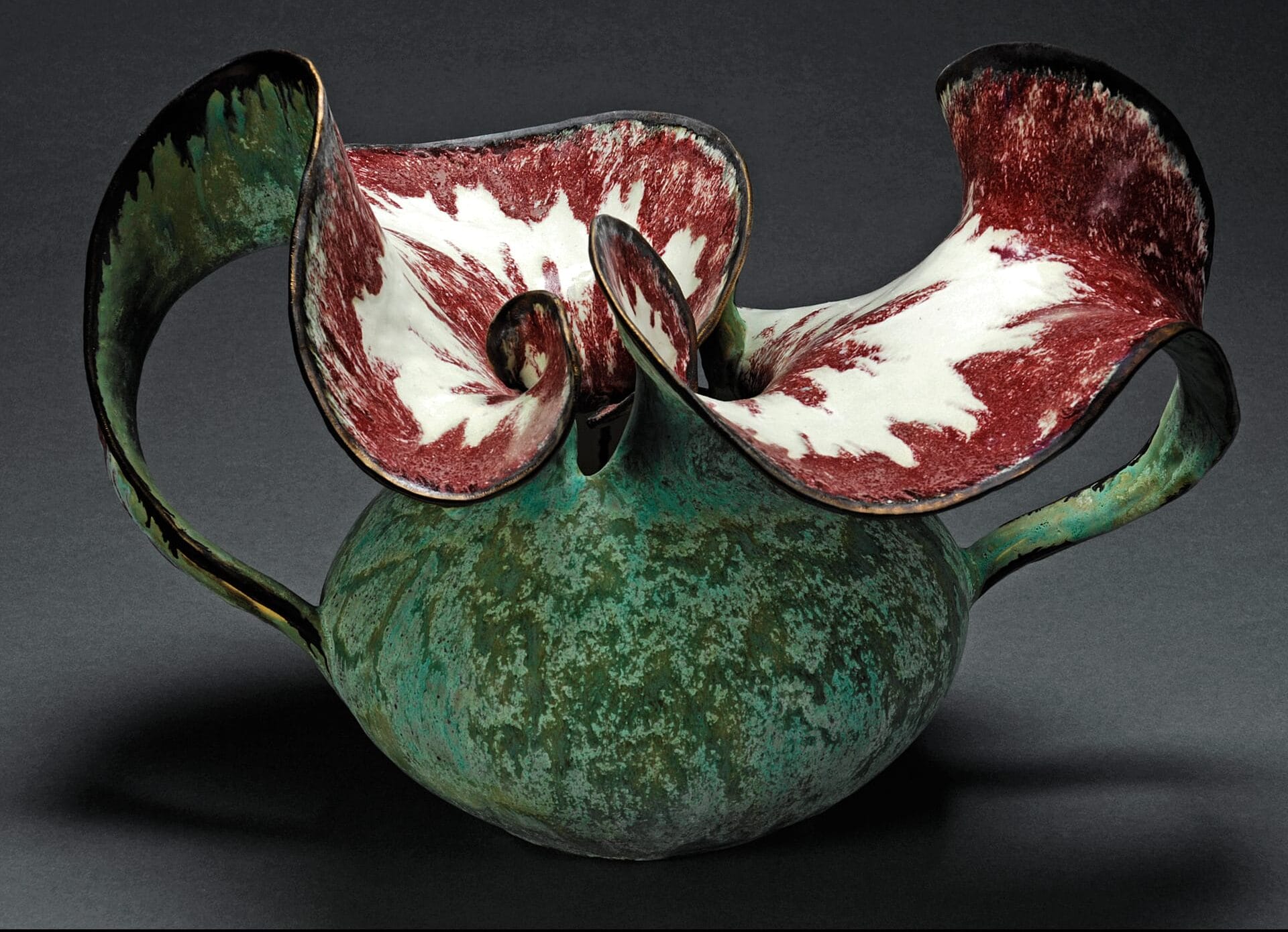 A ceramic vase that is turquoise and red.