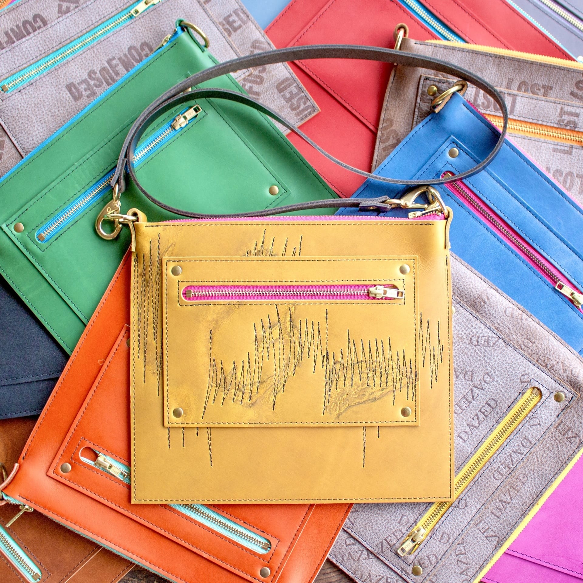 Yellow purse on top of many other colorful purses.
