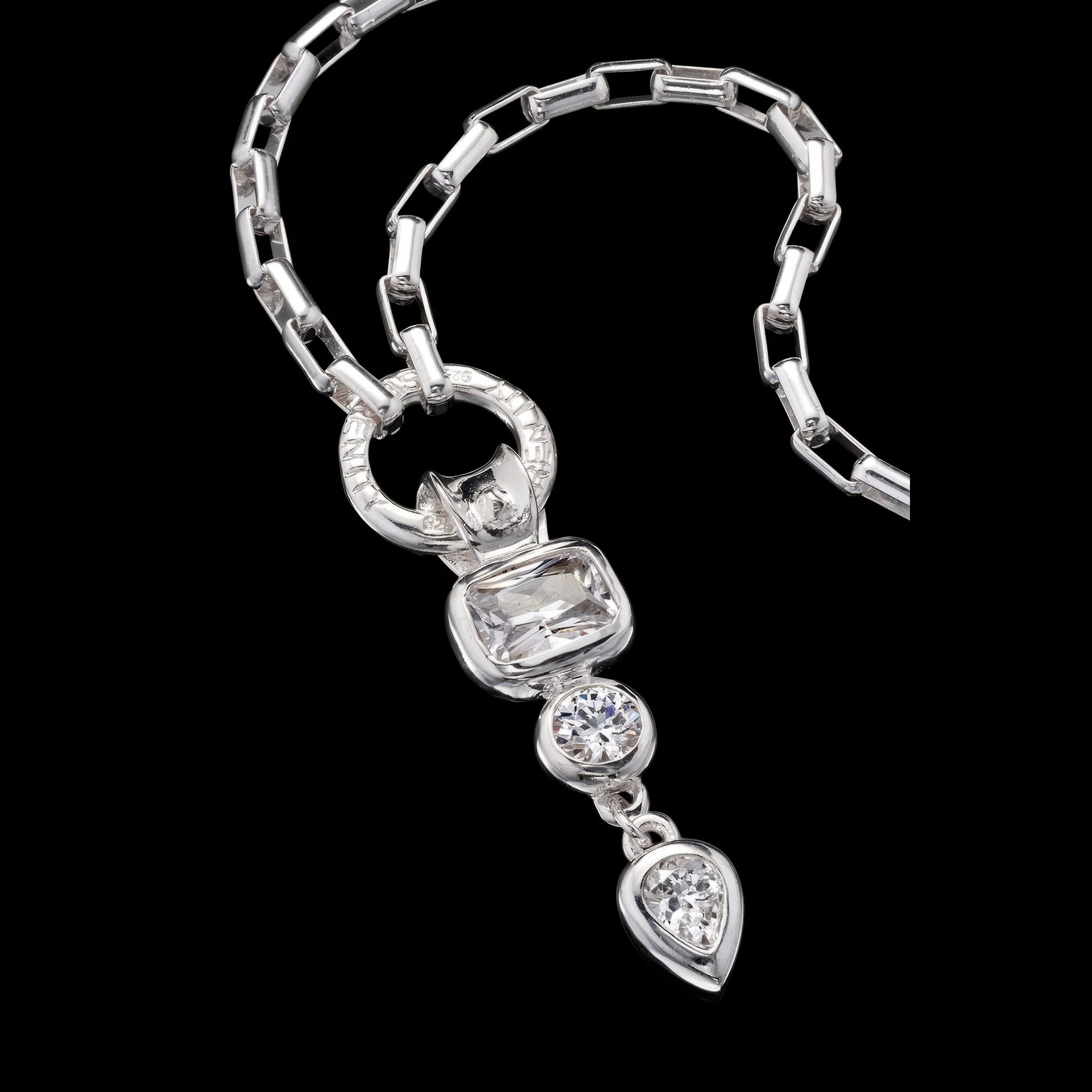A long silver necklace against a black background.