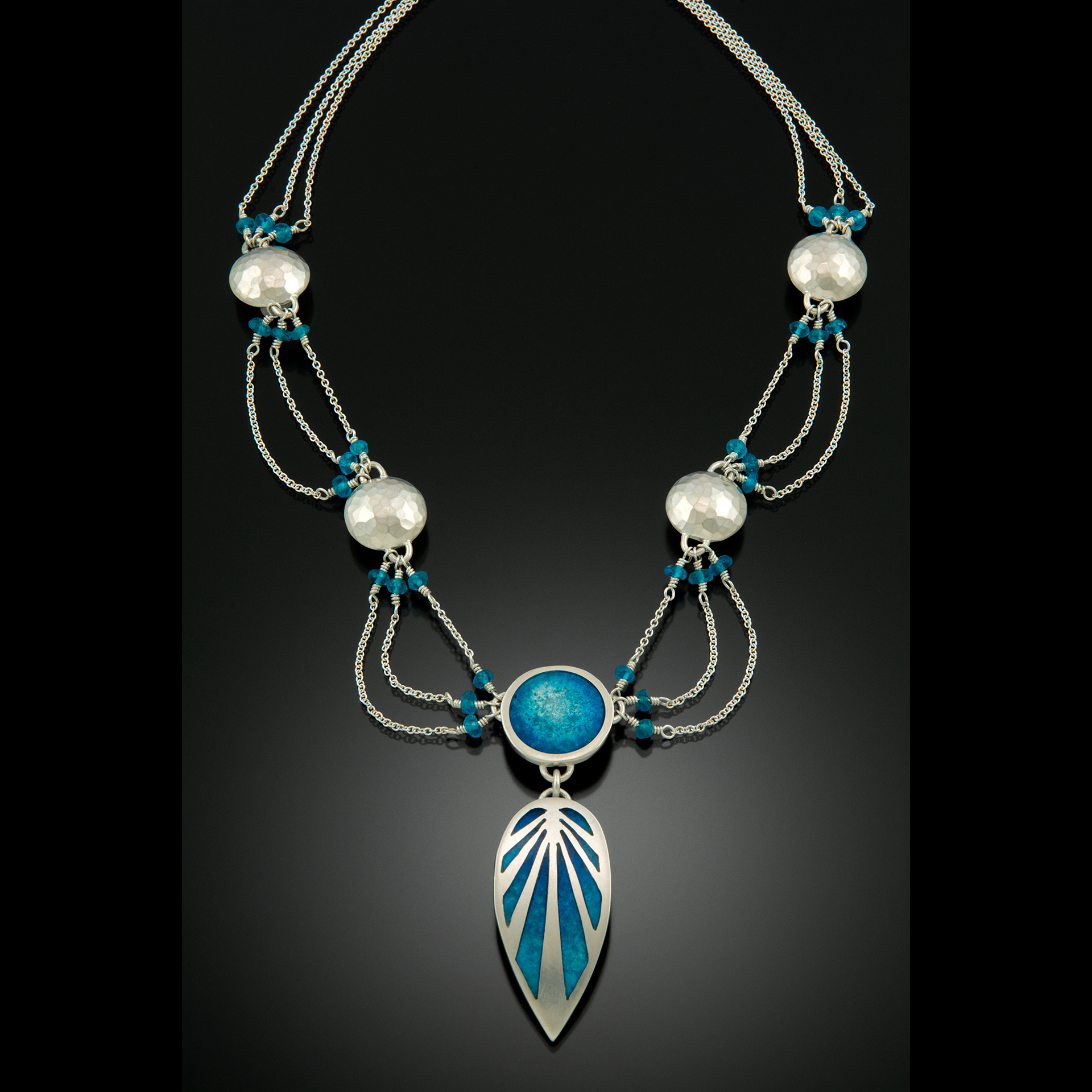 A silver necklace with teal stones.