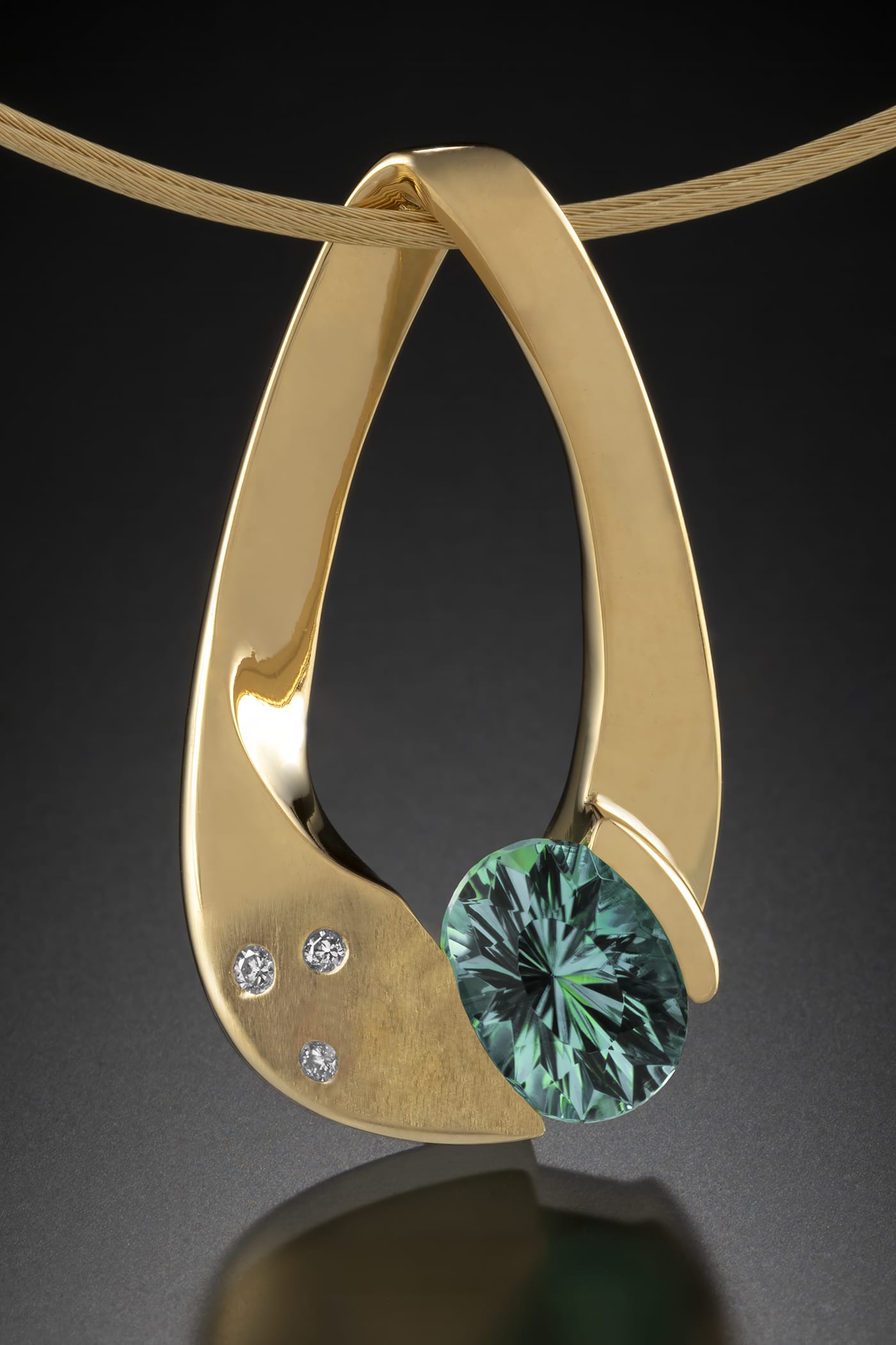 a gold pendant with a green gem