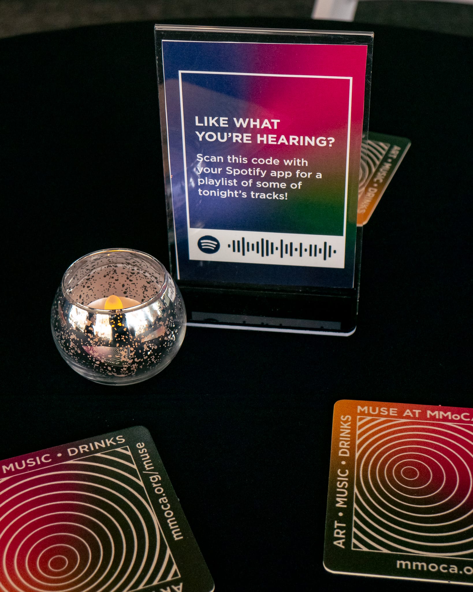 A table with a sign that has a Spotify code on it with lots of gradients.