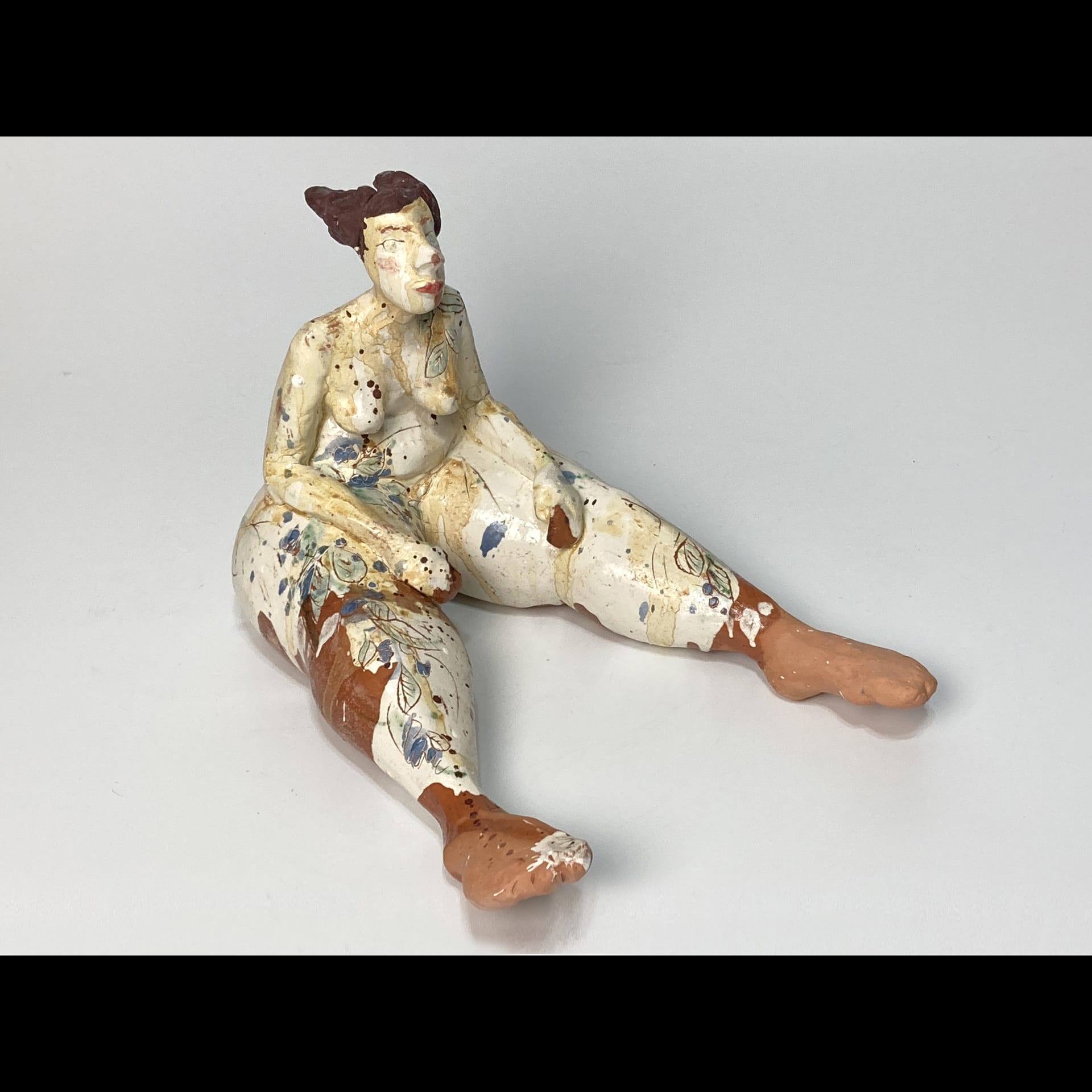 A sculpture of a person sitting on the ground.