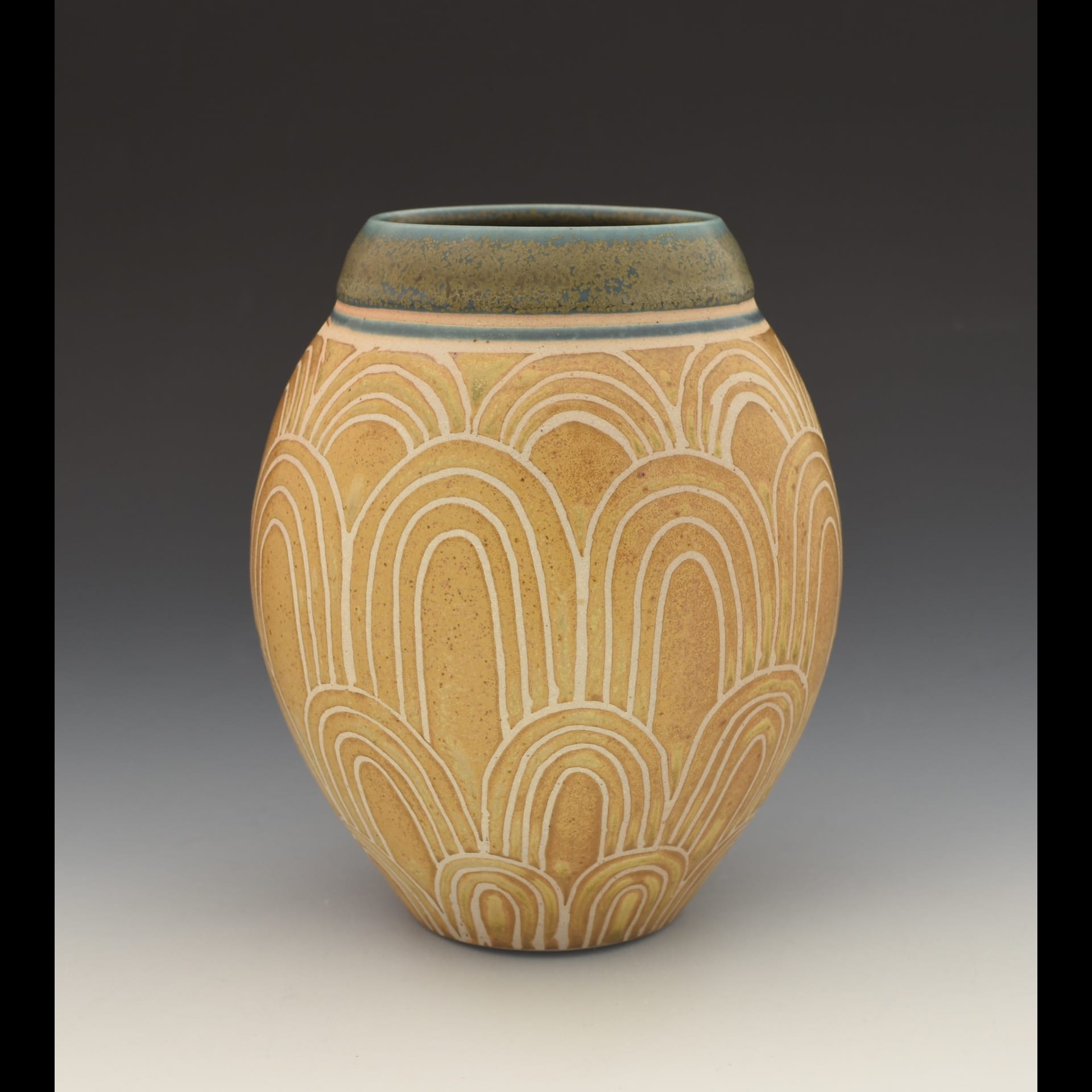 A pot with yellow and white arches carved into it.