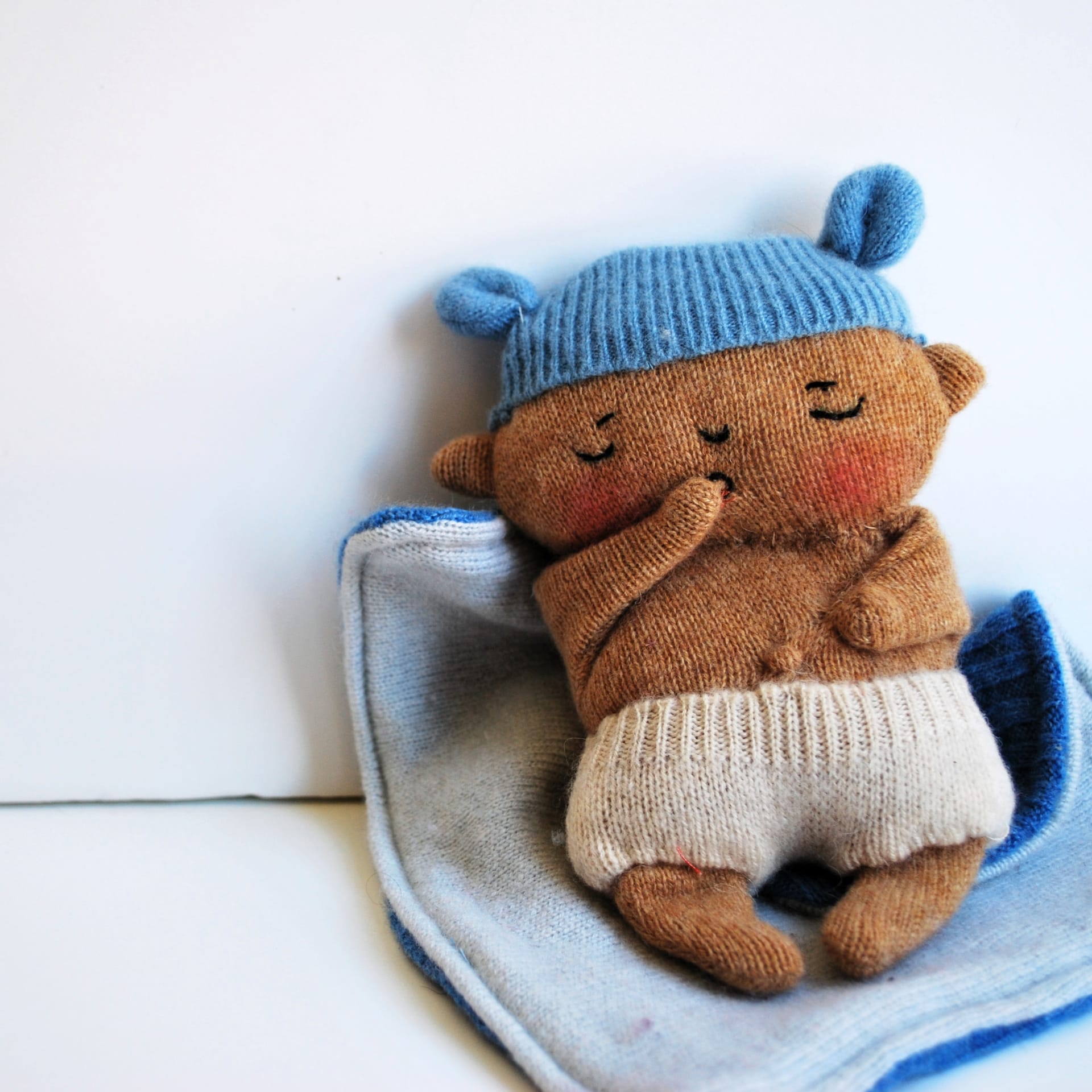 A felt doll of a baby with a blue hat on.