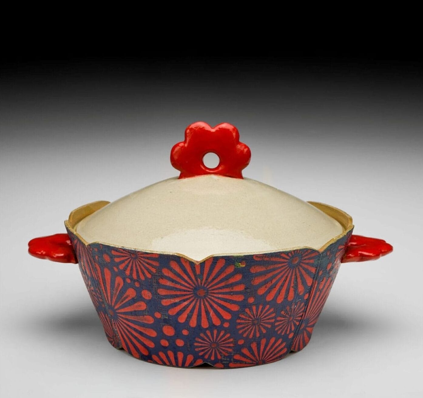 A ceramic pot with a lid that is red and blue.