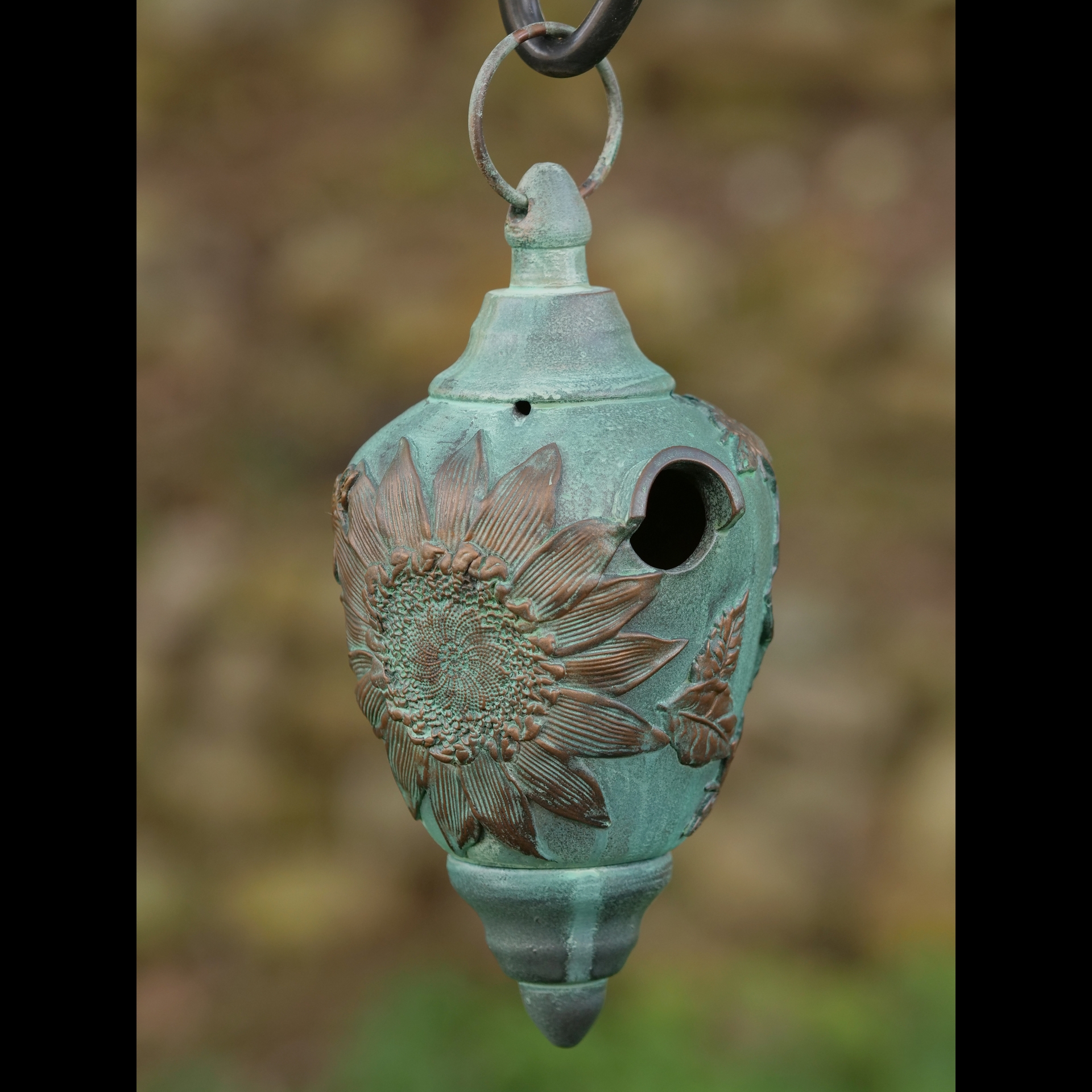 A teal metal bird feeder with a flower on it.