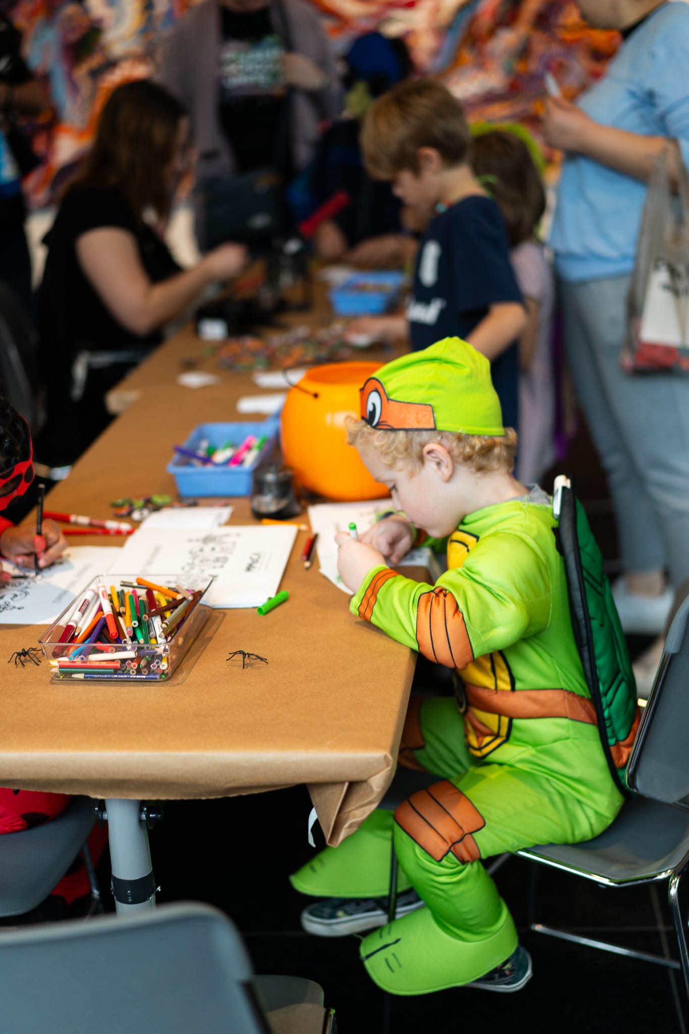 A little kid dressed up in teenage mutant ninja turtle costume while working on an art project.