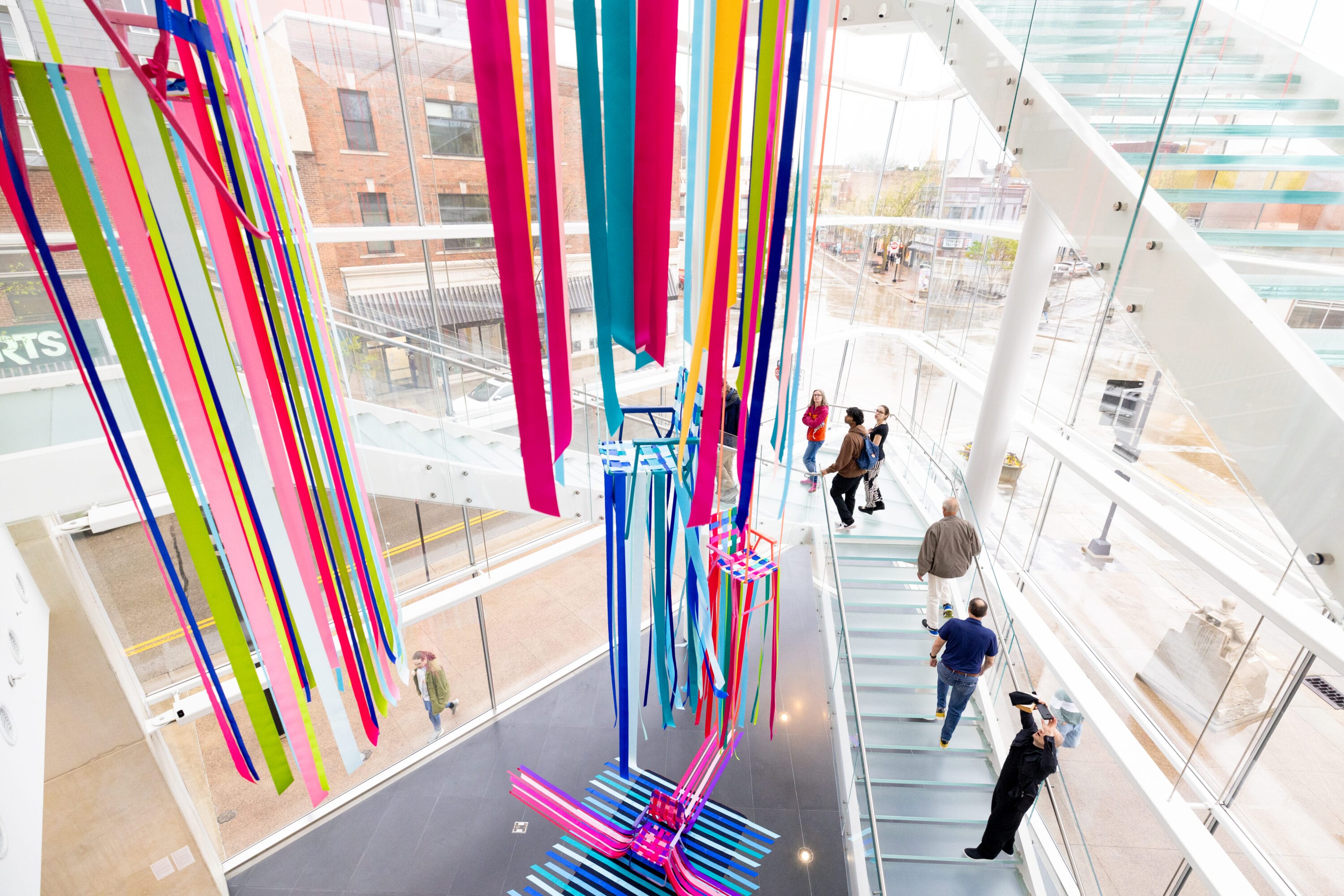The Museum stairwell with John Hitchcocks artworks of chairs with brightly colored ribbons on them. 