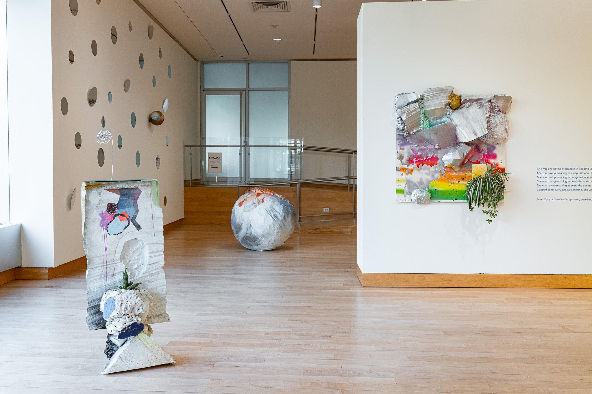 A gallery space with abstract, sculptural art work with a green carpet.