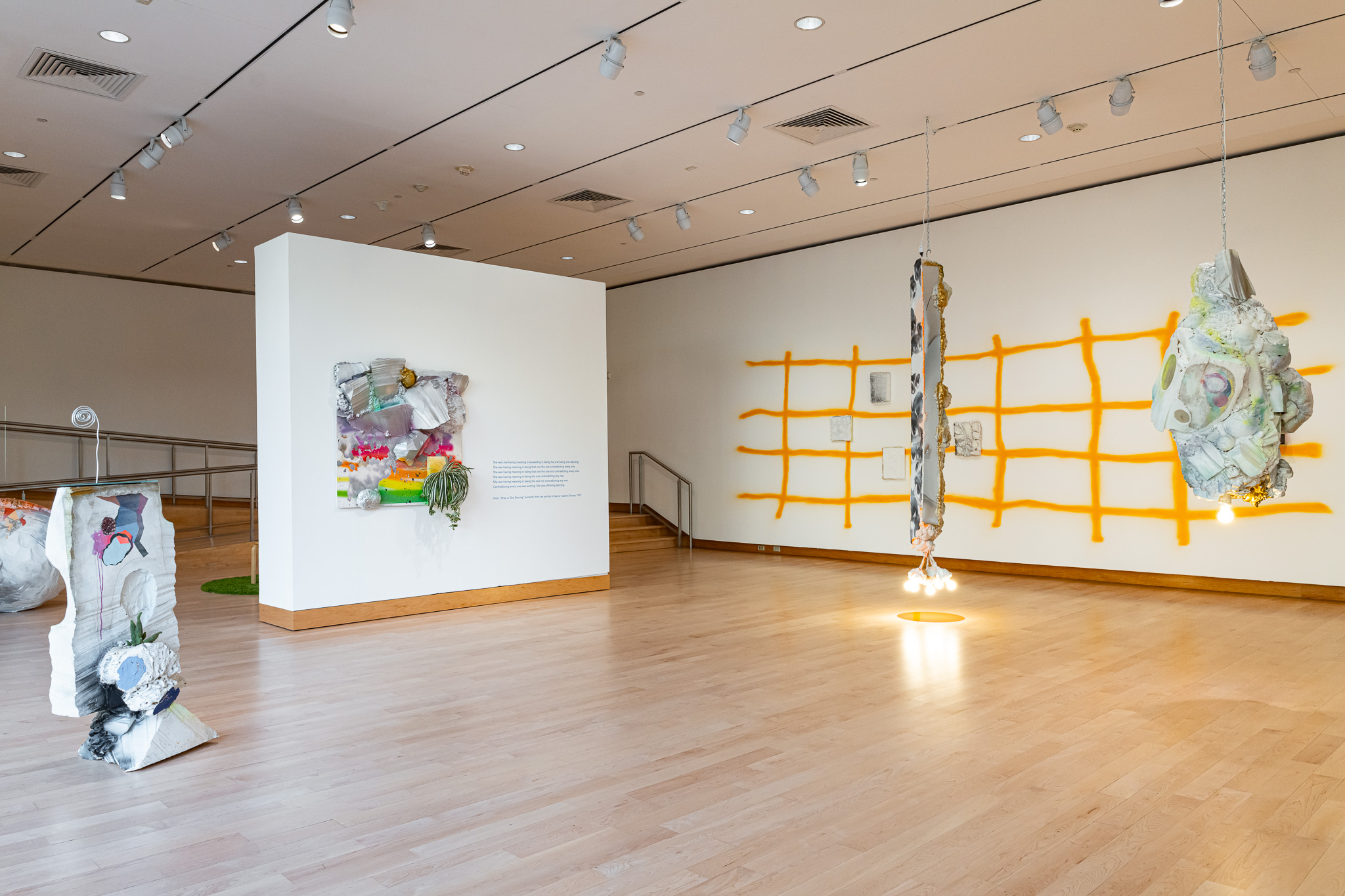 A gallery space with abstract, sculptural art work with a green carpet.