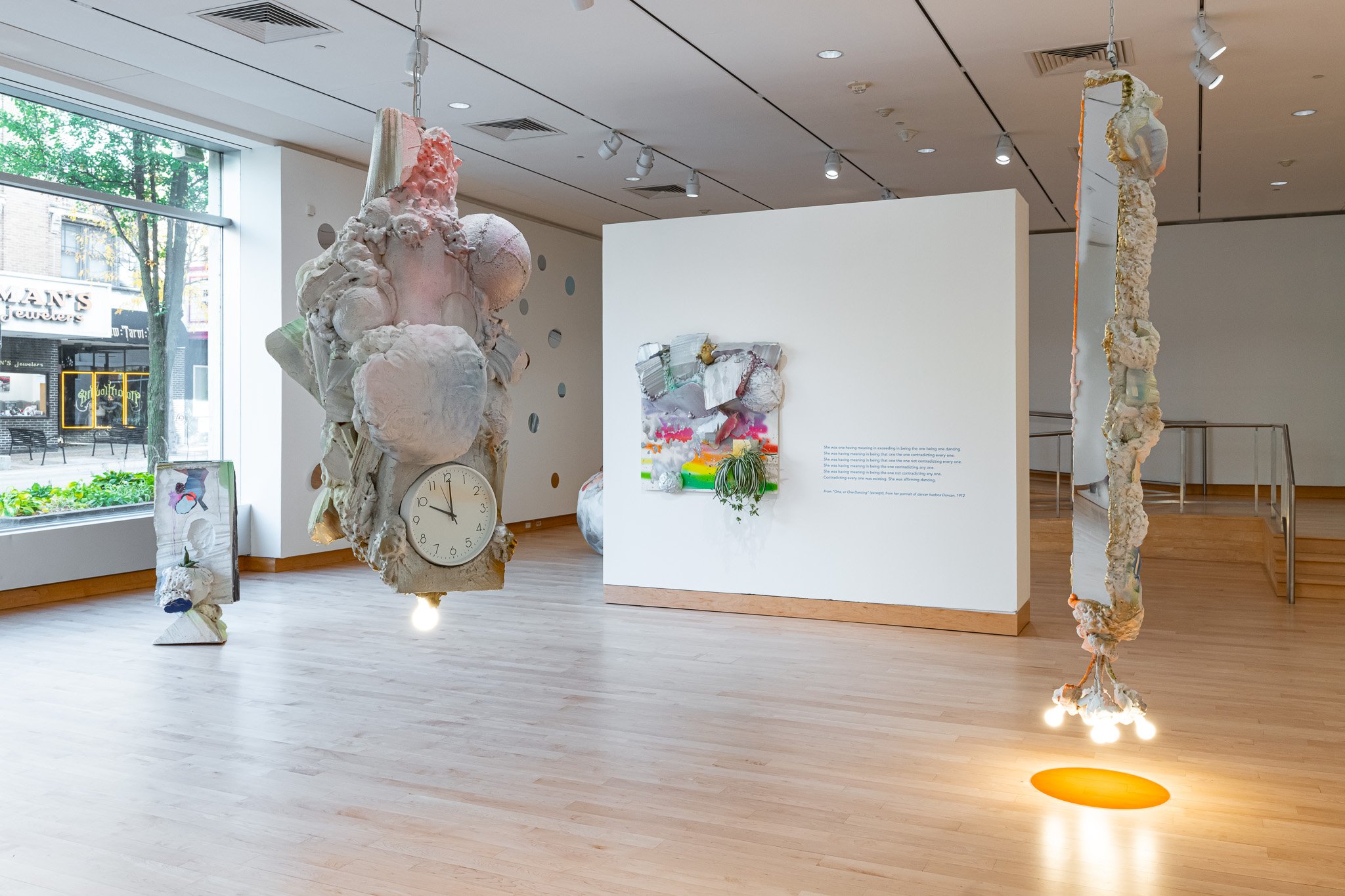 A gallery space with abstract, sculptural art work with a green carpet.