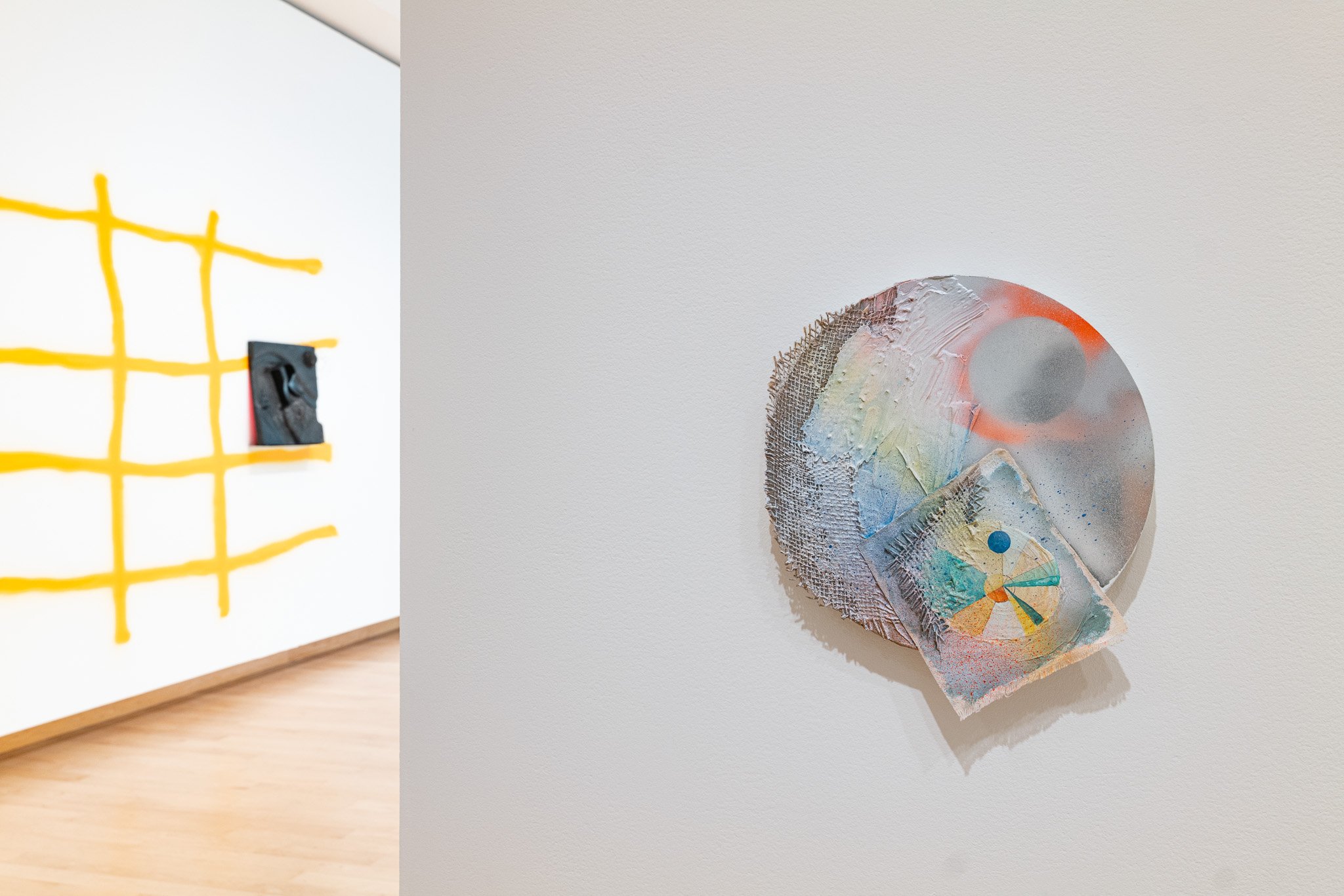 A gallery space with abstract, sculptural art work with a green carpet.