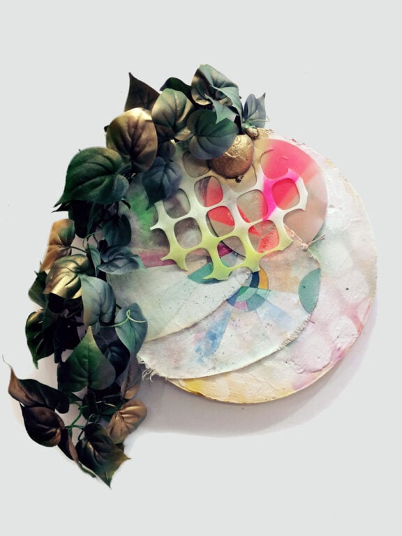 An artwork consisting of overlapping white circles with a a spray-painted plant attached.