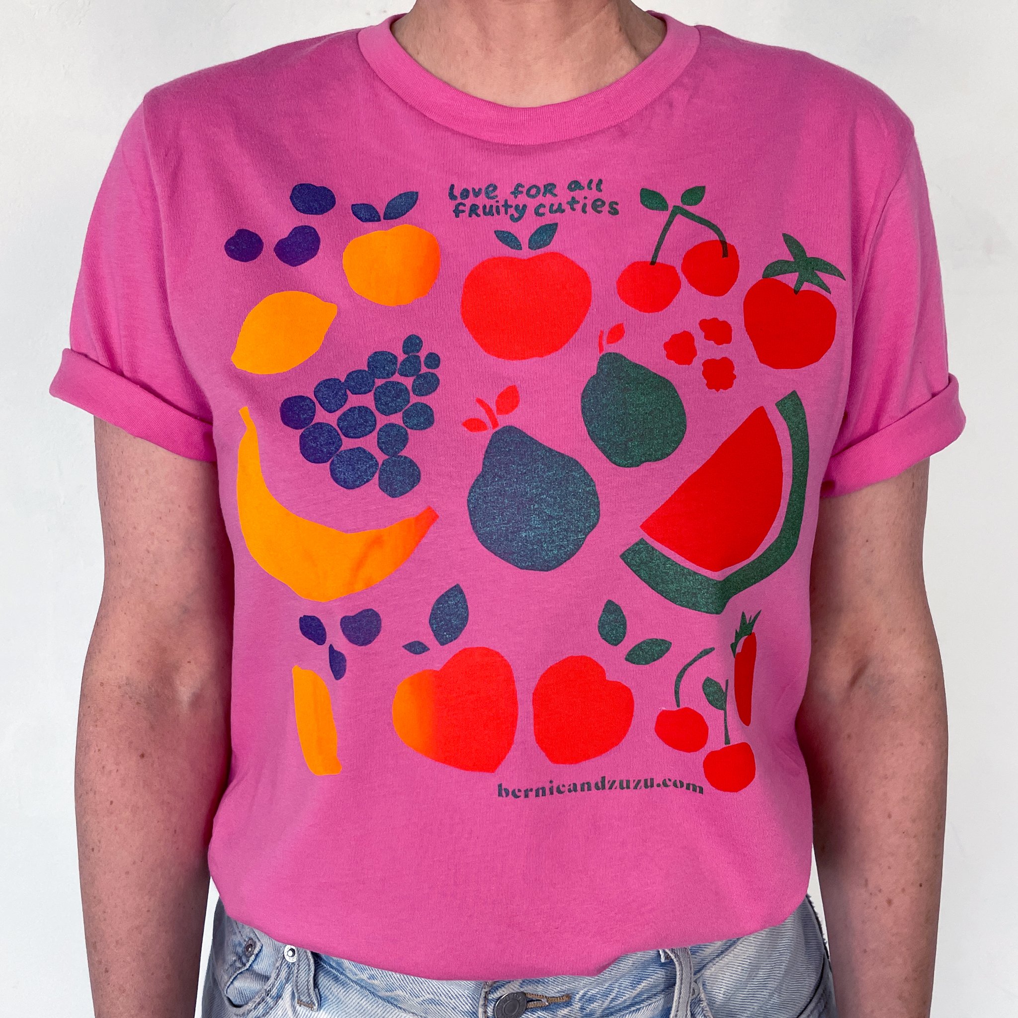 A close up of a pink t-shirt with vairous fruit on it and the text reads I love all my fruity cuties. 