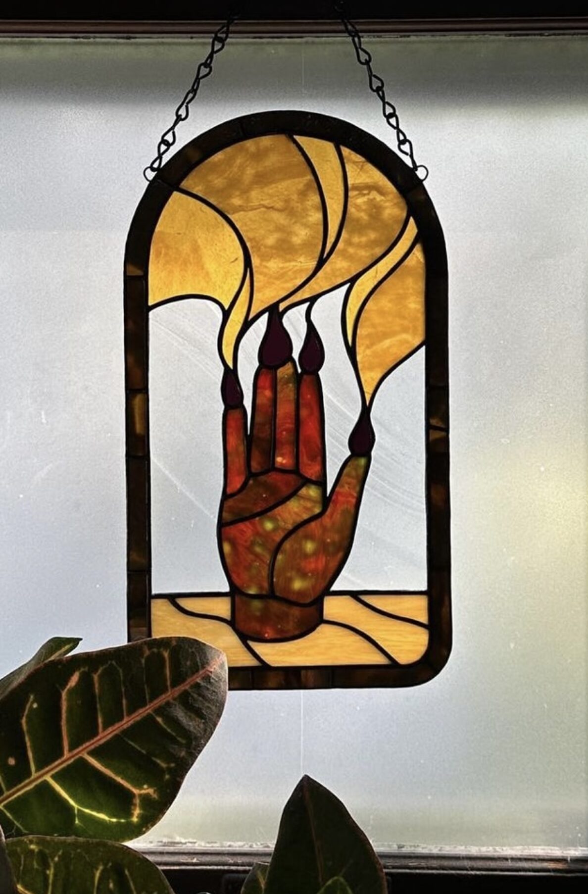 A stained glass window of a hand with smoke from the finger. 