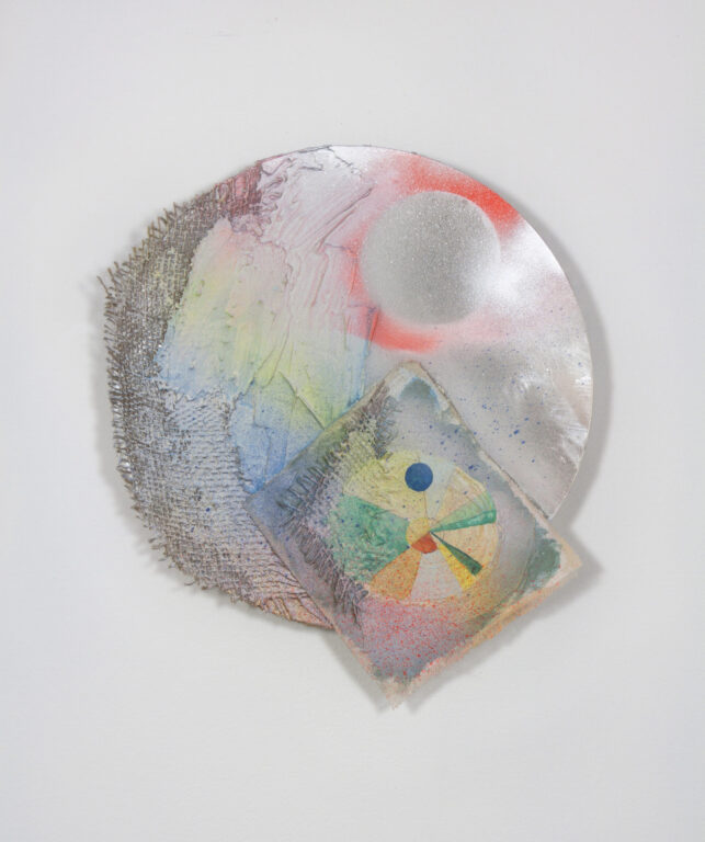 A silver disk with painted pink, orange and green parts.