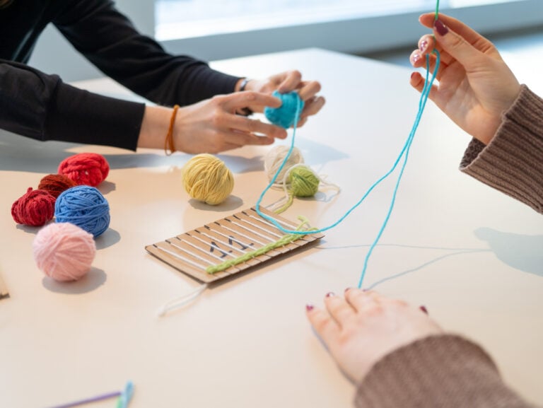 People working with yarn to make a loom.