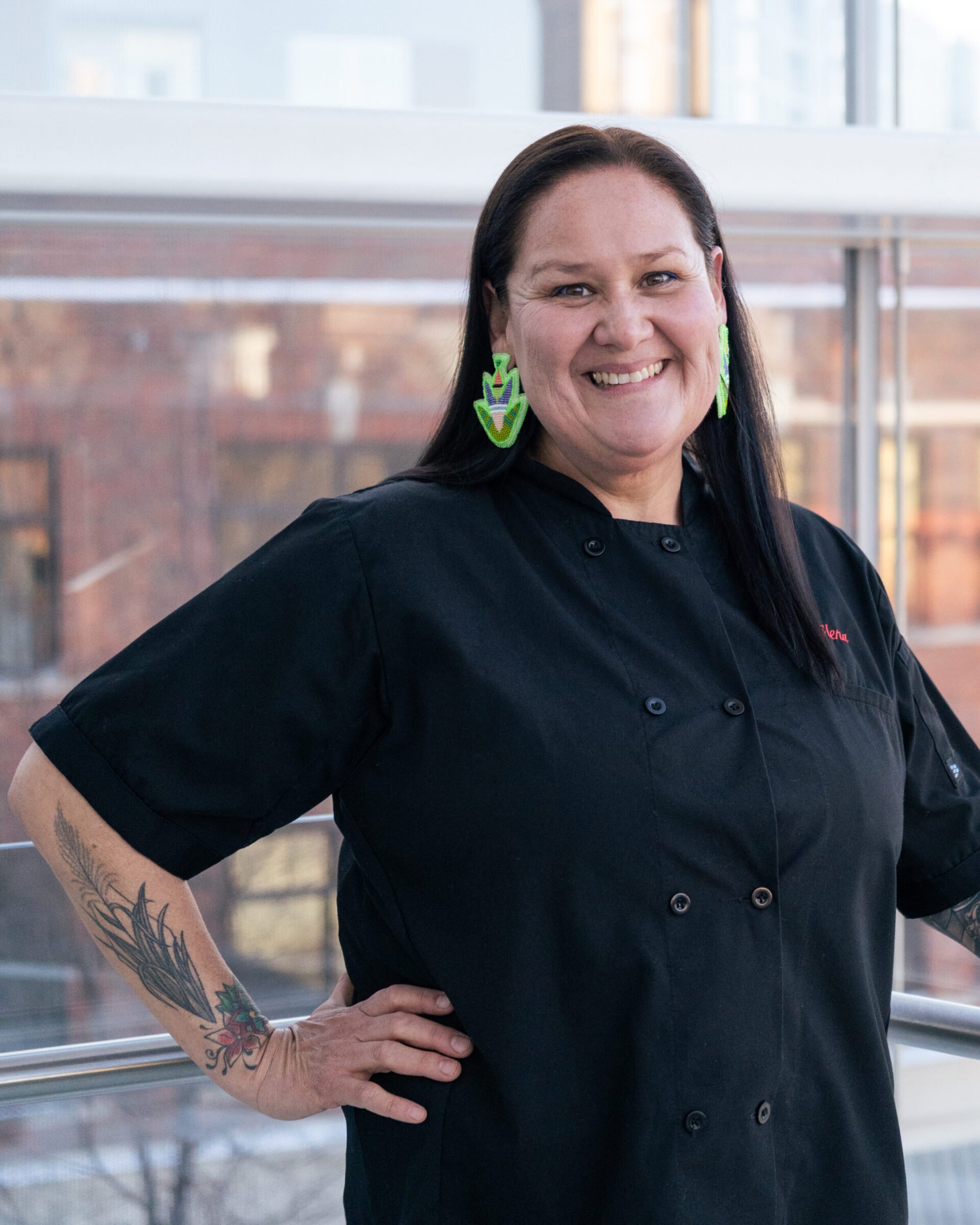 A person smiling in a black chef uniform.