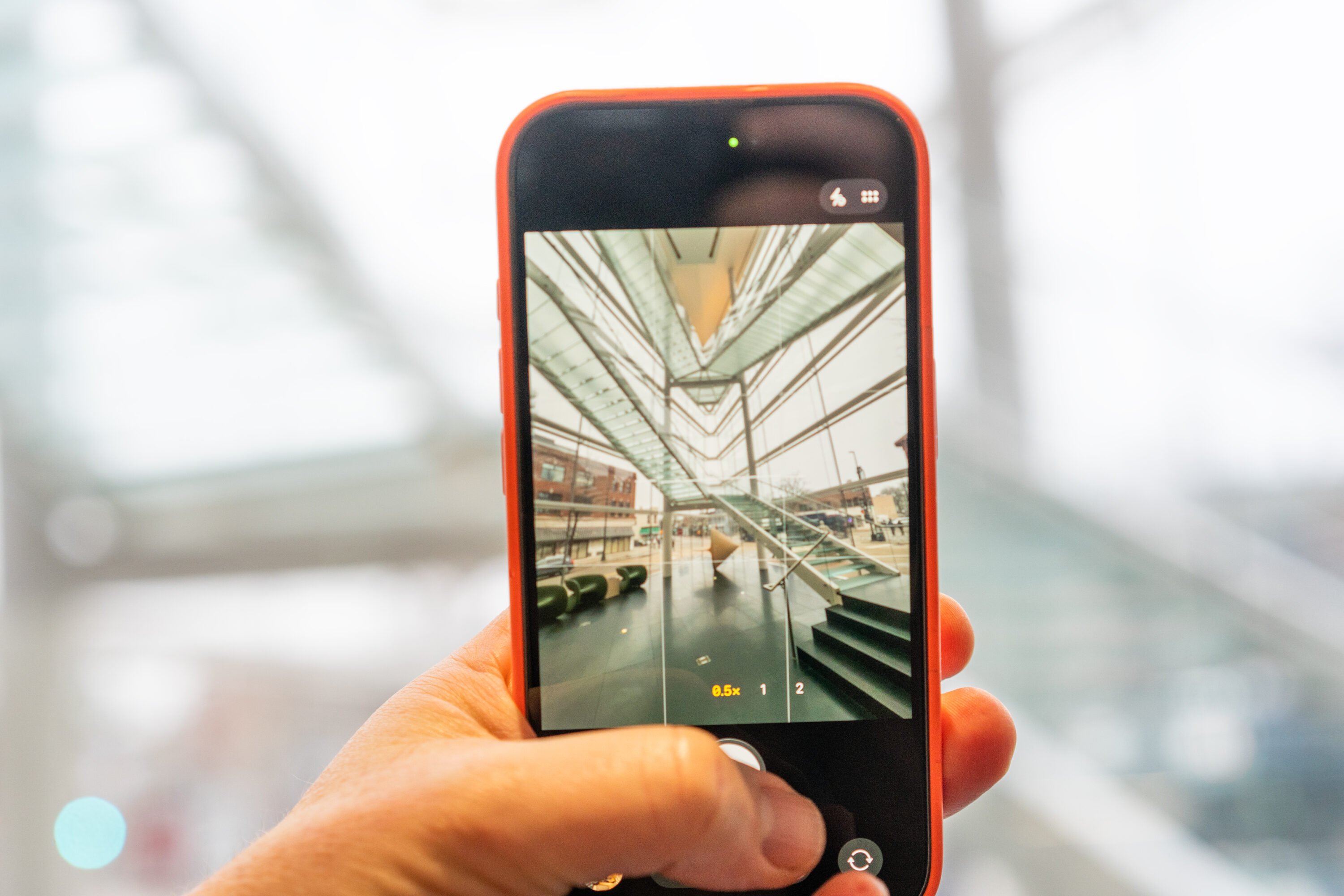 A hand holds an iphone, on the screen is the photo app showing an image of the museum.