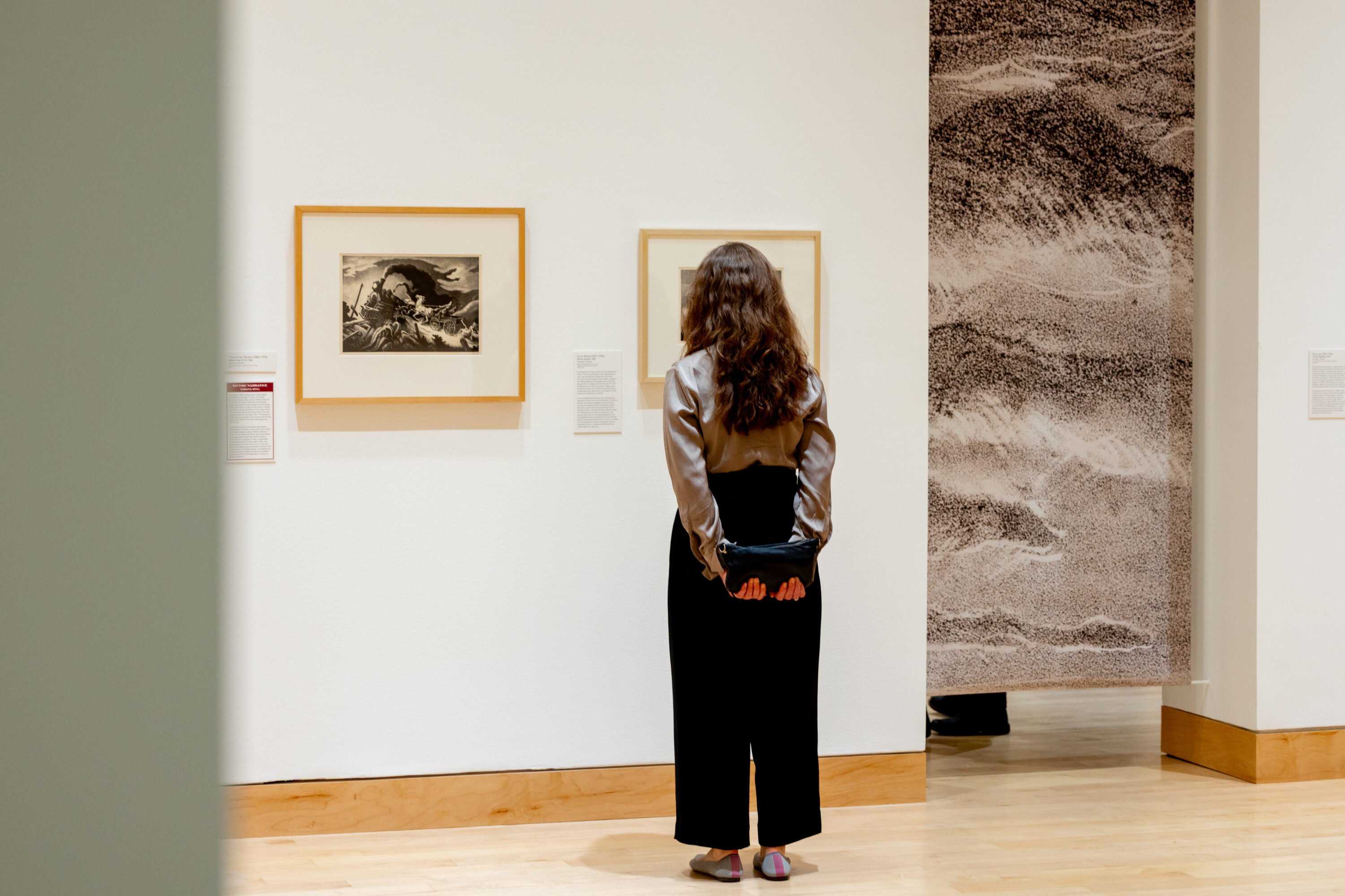 Someone in a gallery looking at artwork on the wall.