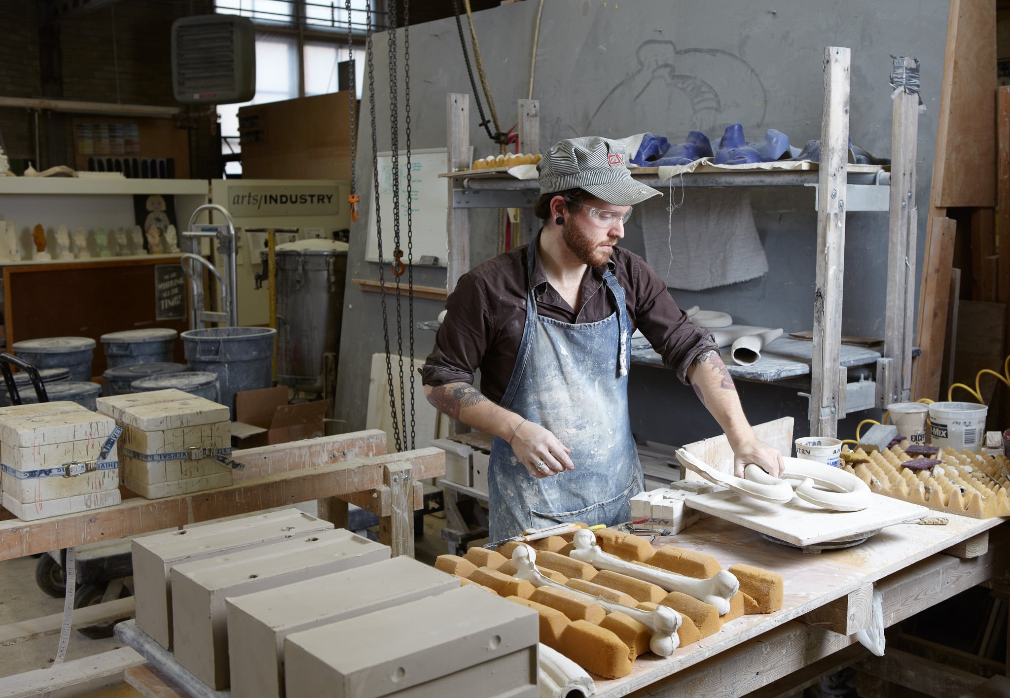 A man in a work shop casting bone sculptures.