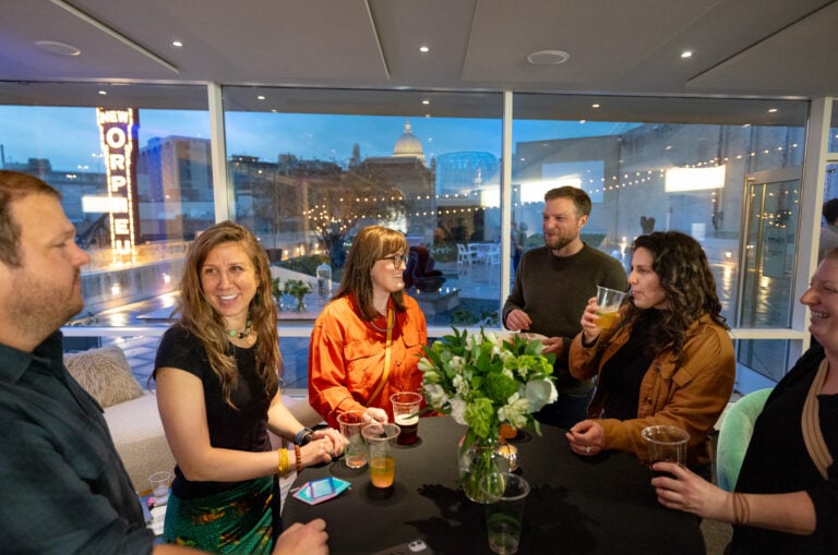 People smiling around a table while drinking cocktails.